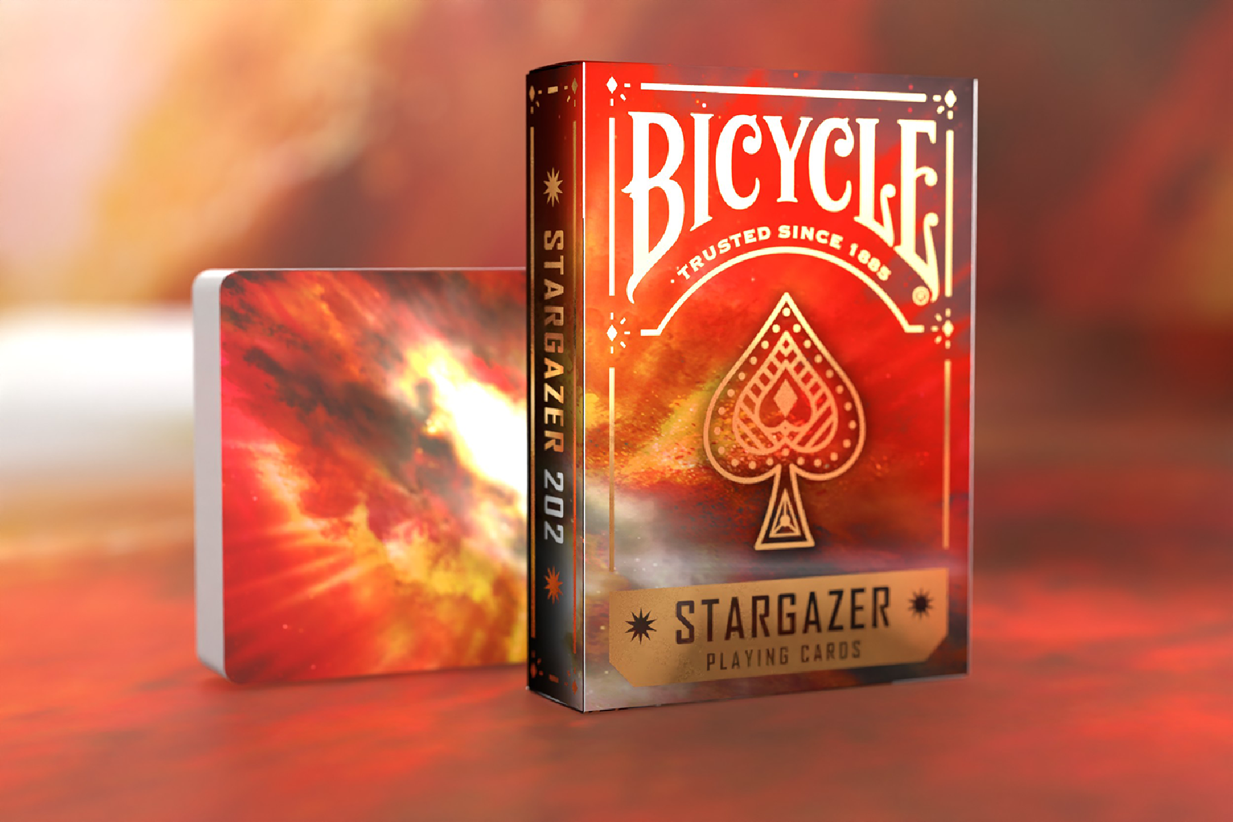 Ein Deck Bicycle Stargazer Spielkarten mit rotem und goldenem Design. Ein weiteres Deck ist sichtbar.