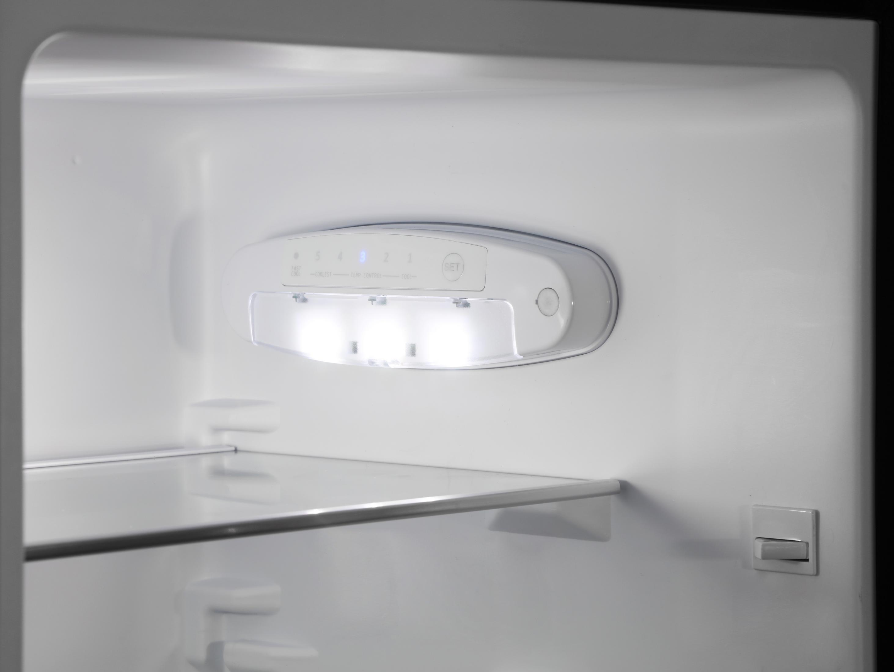 Im Inneren eines Kühlschranks, mit einer Lichtleiste und einem Glasregal. Weißer Innenraum mit heller Beleuchtung.