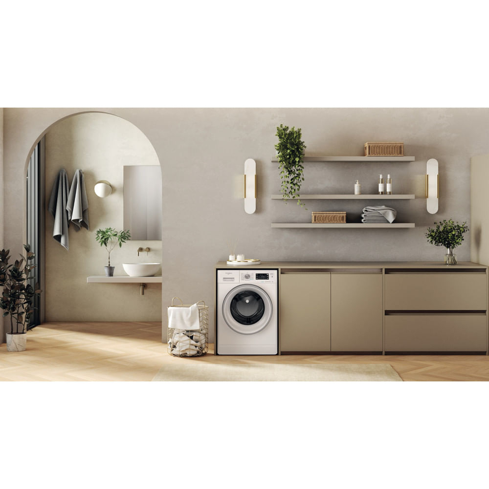 Bagno moderno con lavatrice, piante e tonalità neutre.