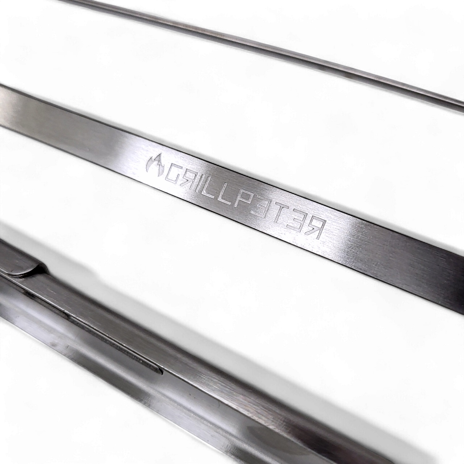 Drei Grill-Spatel aus Metall. Der mittlere Spatel hat den Text "GRILLPATER" eingraviert.