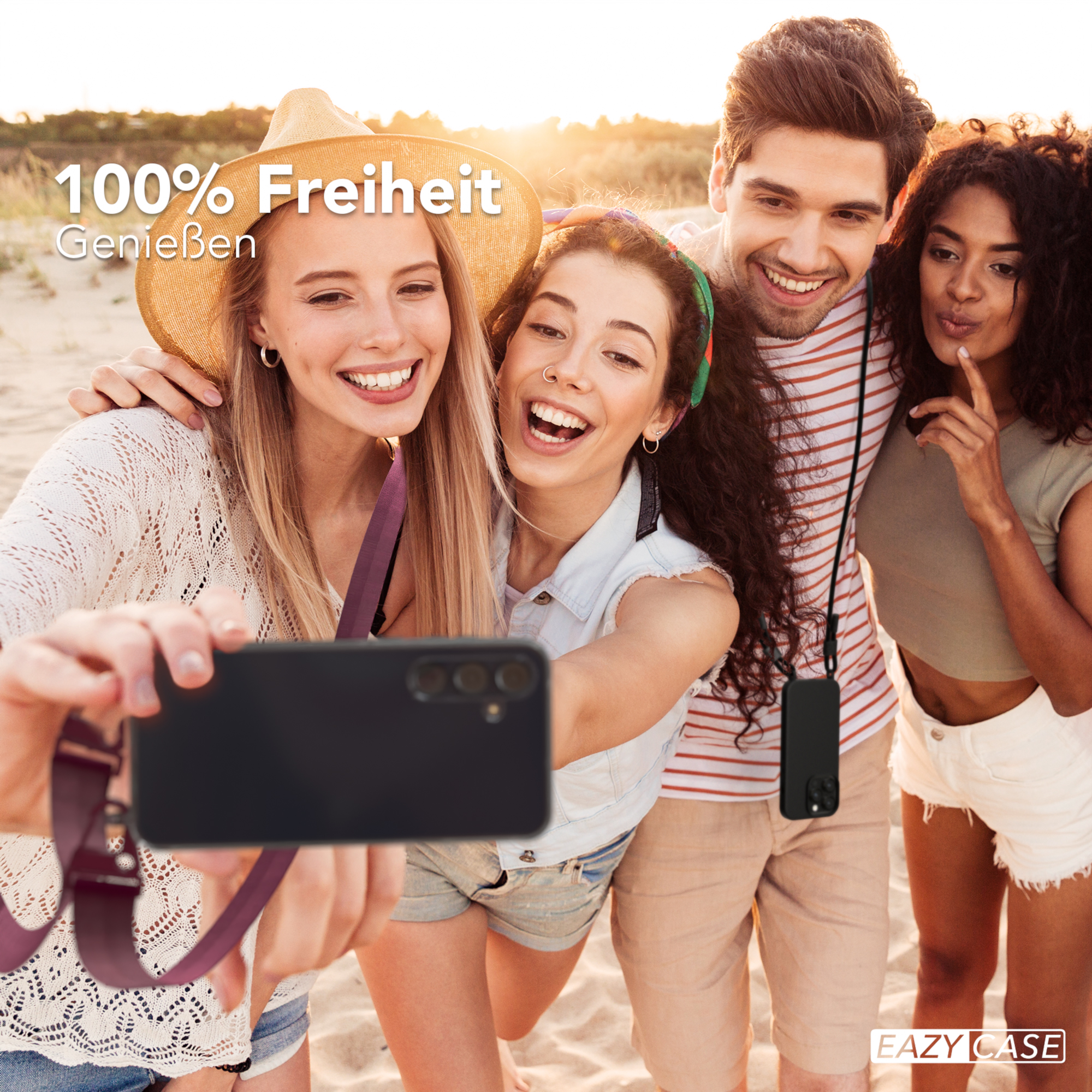 Vier Personen lächeln und machen ein Selfie am Strand. Eine Person hält das Telefon mit einem Riemen.