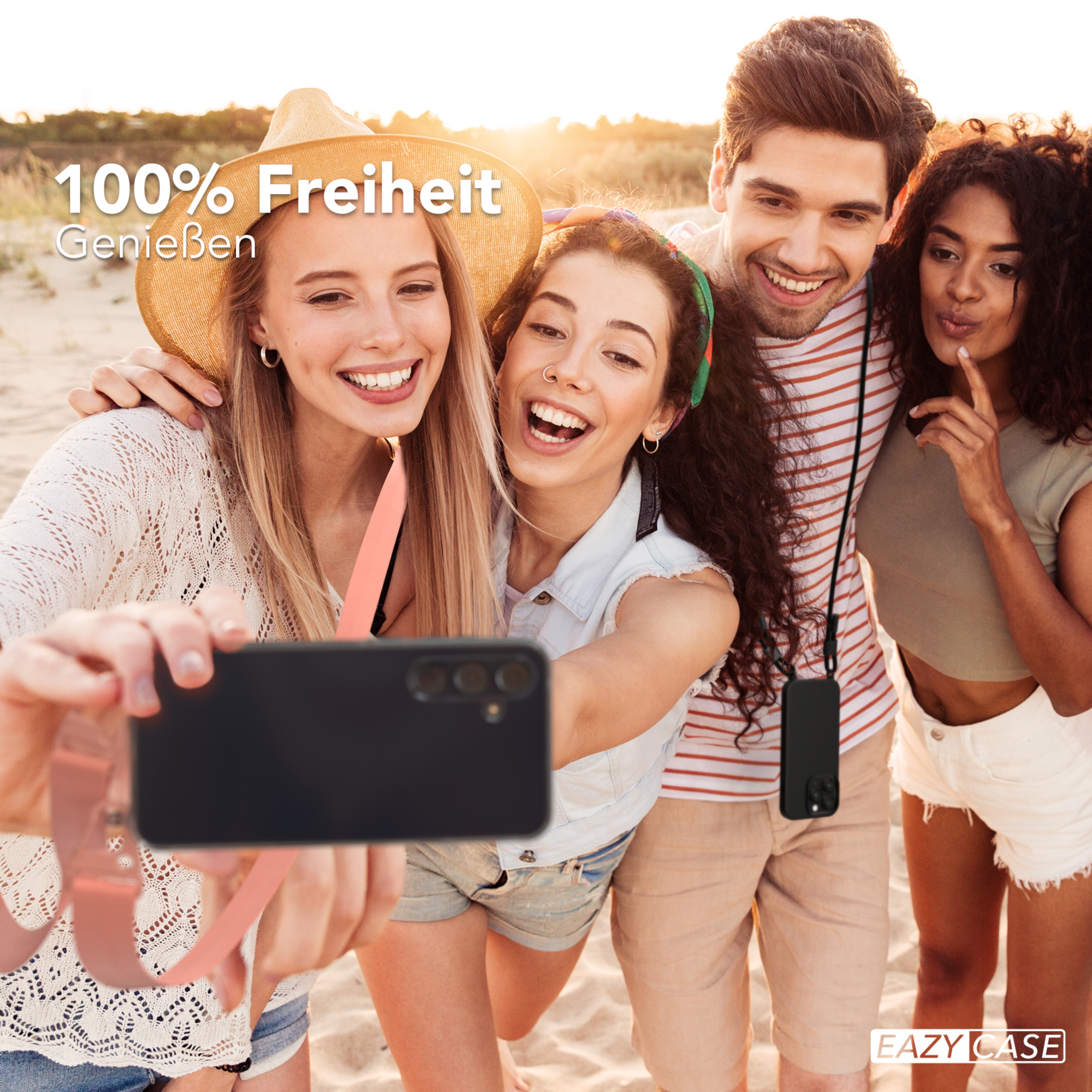 Vier Personen machen ein Selfie am Strand. Sie lächeln, halten ein Telefon mit Band und tragen Strandkleidung.