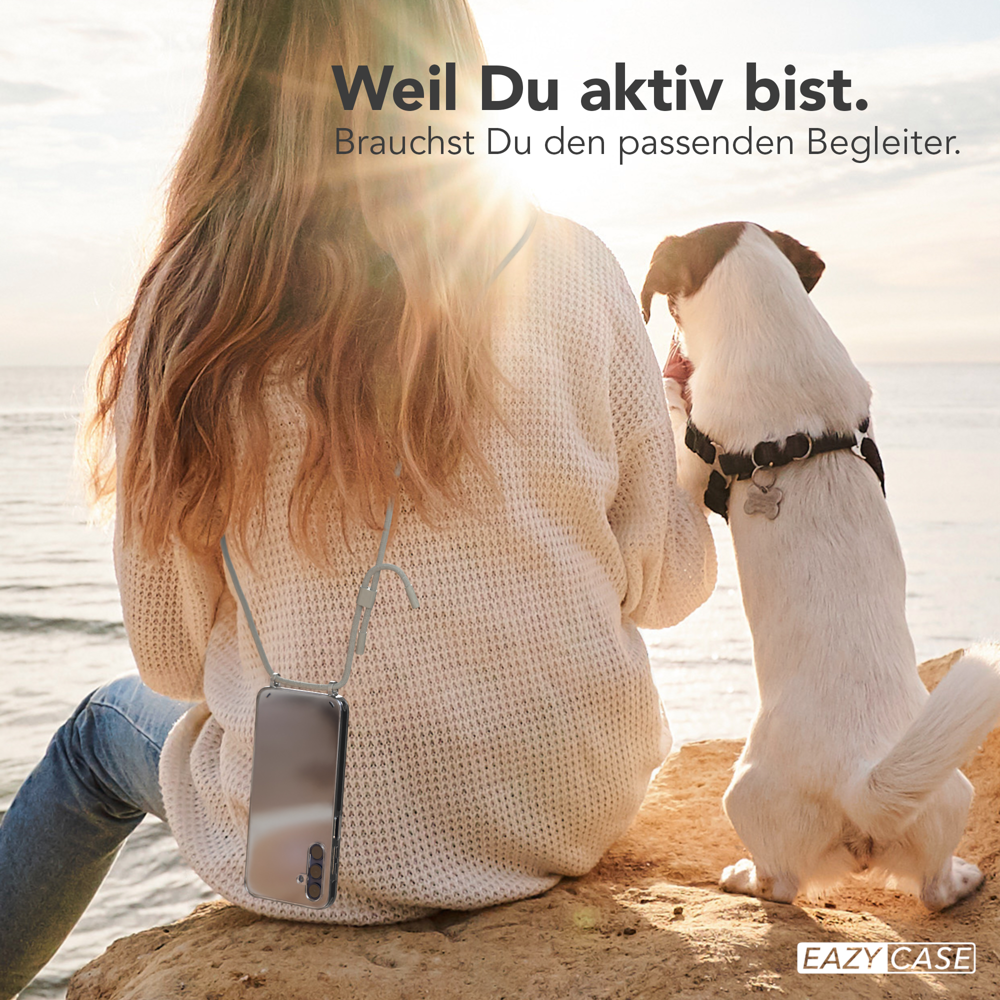 Eine Frau sitzt auf einem Felsen, mit einem hängenden Telefon und einem Hund, der sie ansieht.