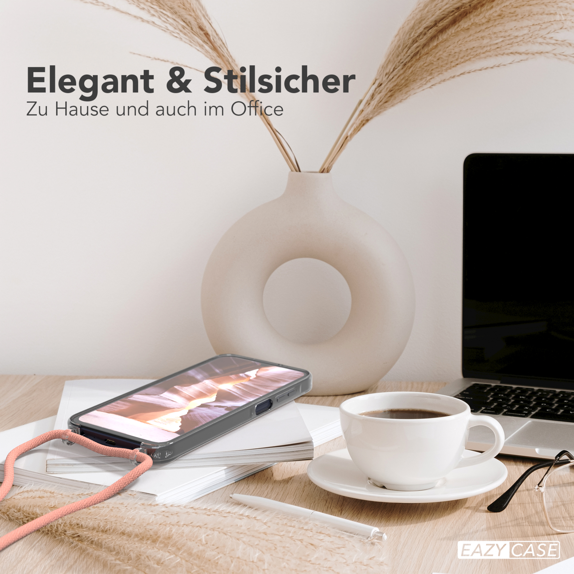 Ein Telefon mit Hülle und Band auf einem Schreibtisch mit Kaffeetasse, Stift und Laptop.