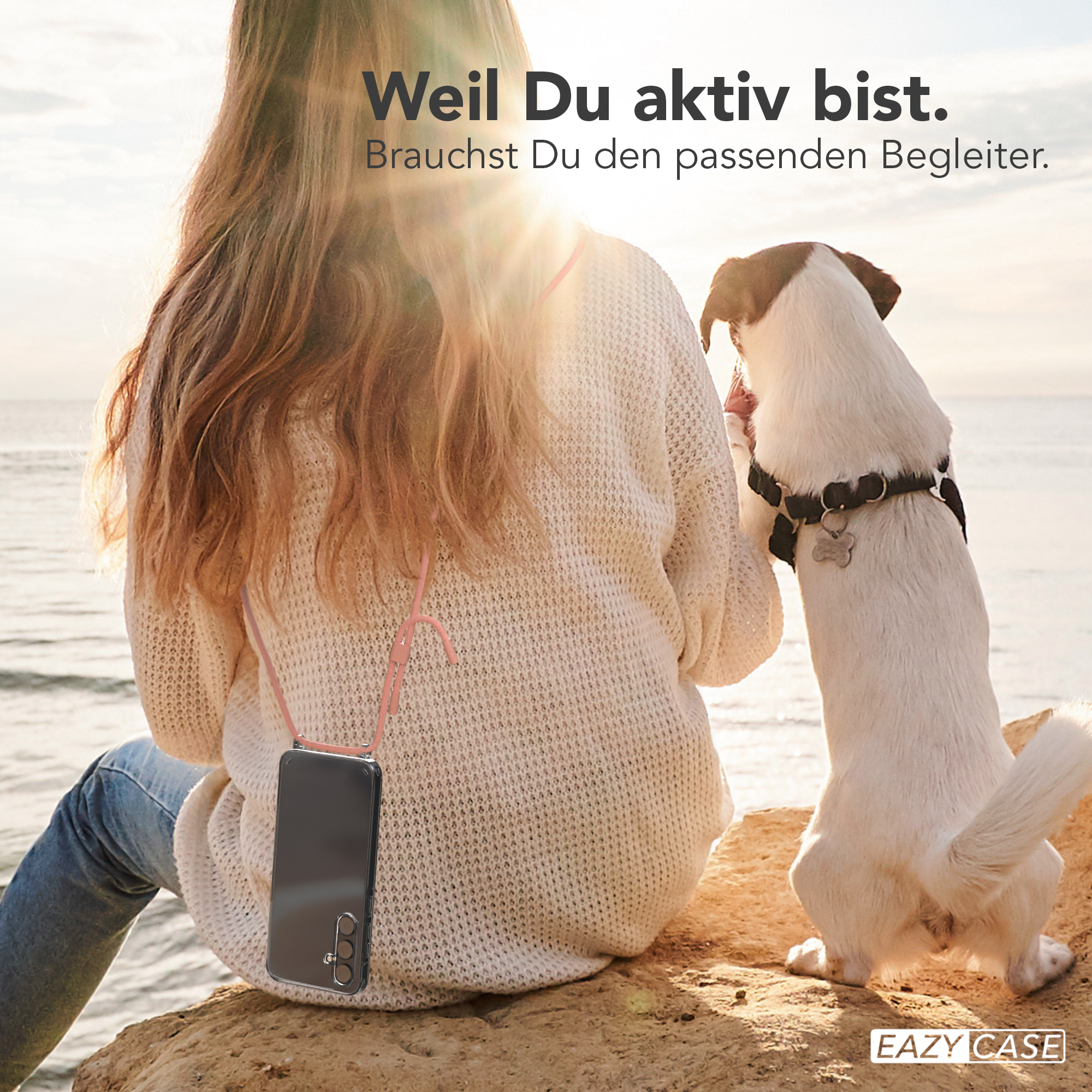 Eine Frau und ein Hund sind am Strand. Die Frau hält ein Telefon mit rosa Riemen.