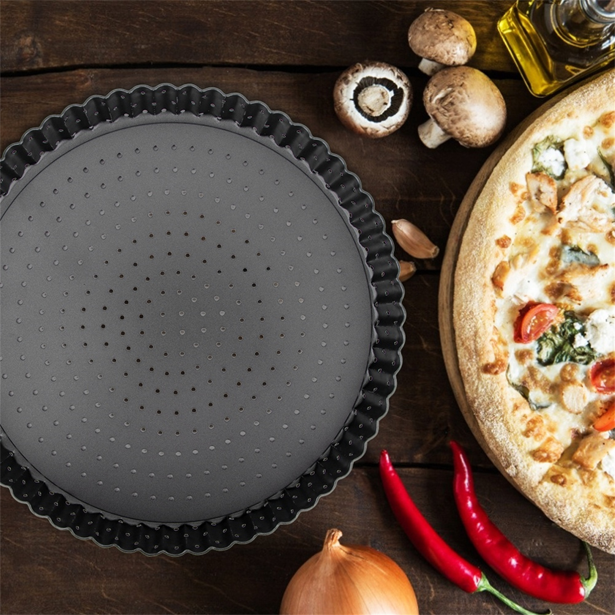 Eine dunkelgraue Kuchenform mit Perforationen und Pizza mit Pilzen, Tomaten und Basilikum.