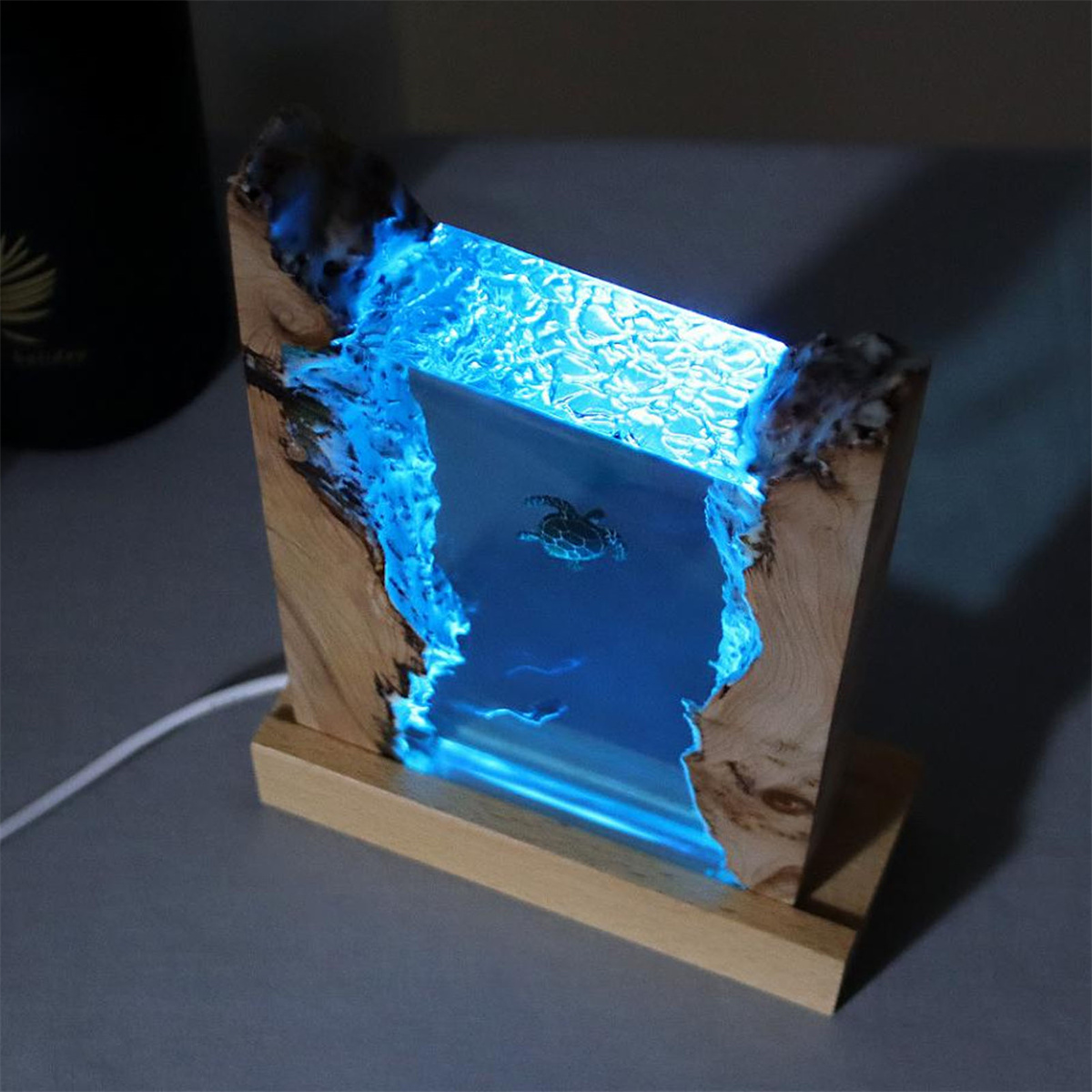 Holzkunstwerk mit leuchtend blauem Inneren, das eine Meeresschildkröte im Wasser darstellt.