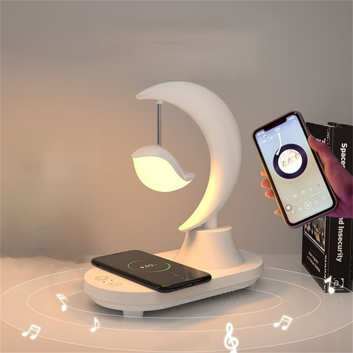 Weiße mondförmige Lampe mit Telefonaufladung und einem Musik abspielenden Telefon.