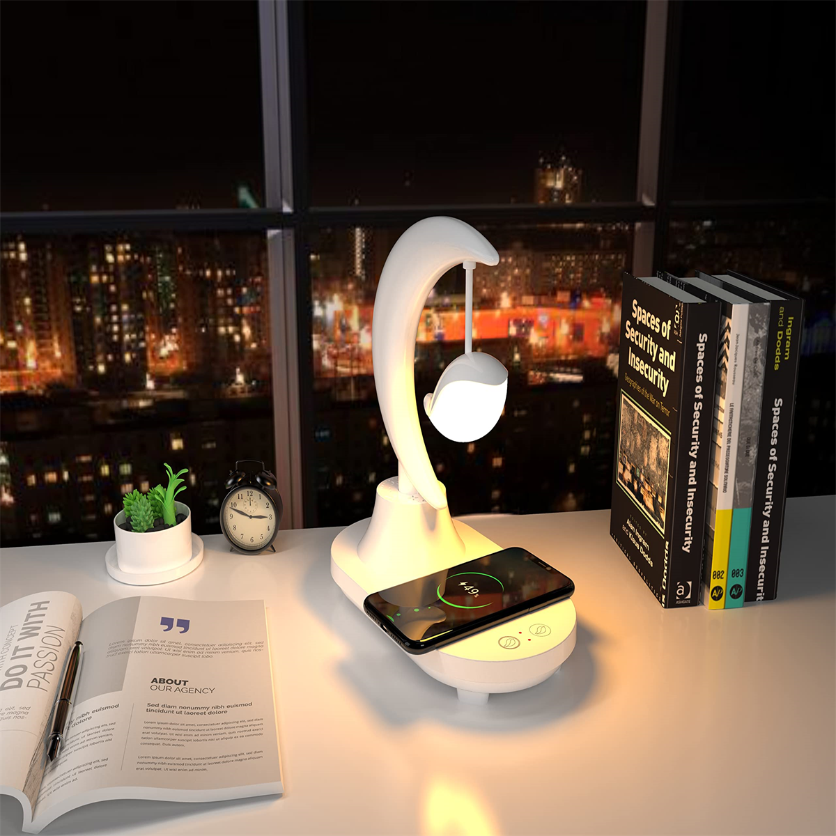 Weißer Schreibtisch mit Lampe, Telefon, Büchern und Pflanze, mit Stadtbild draußen.