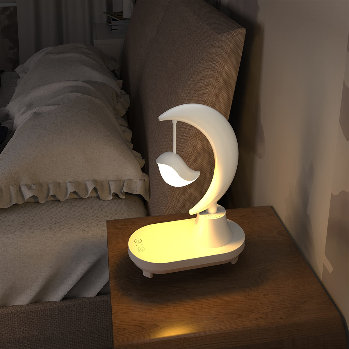 Eine weiß-gelbe mondförmige Nachtlampe auf einem hölzernen Nachttisch neben einem Bett.