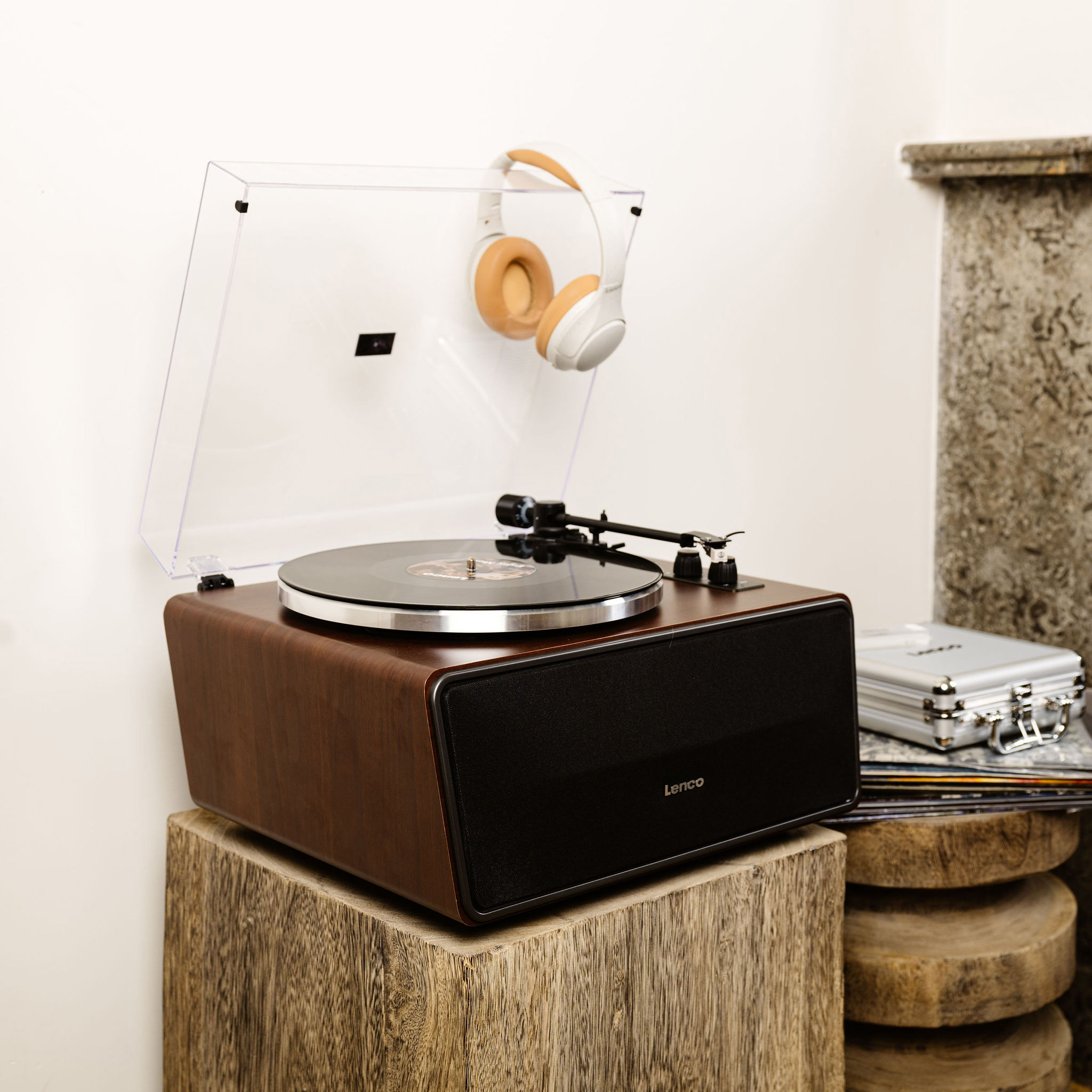 Drewniany gramofon z przezroczystą pokrywą, słuchawkami i stos płyt.
