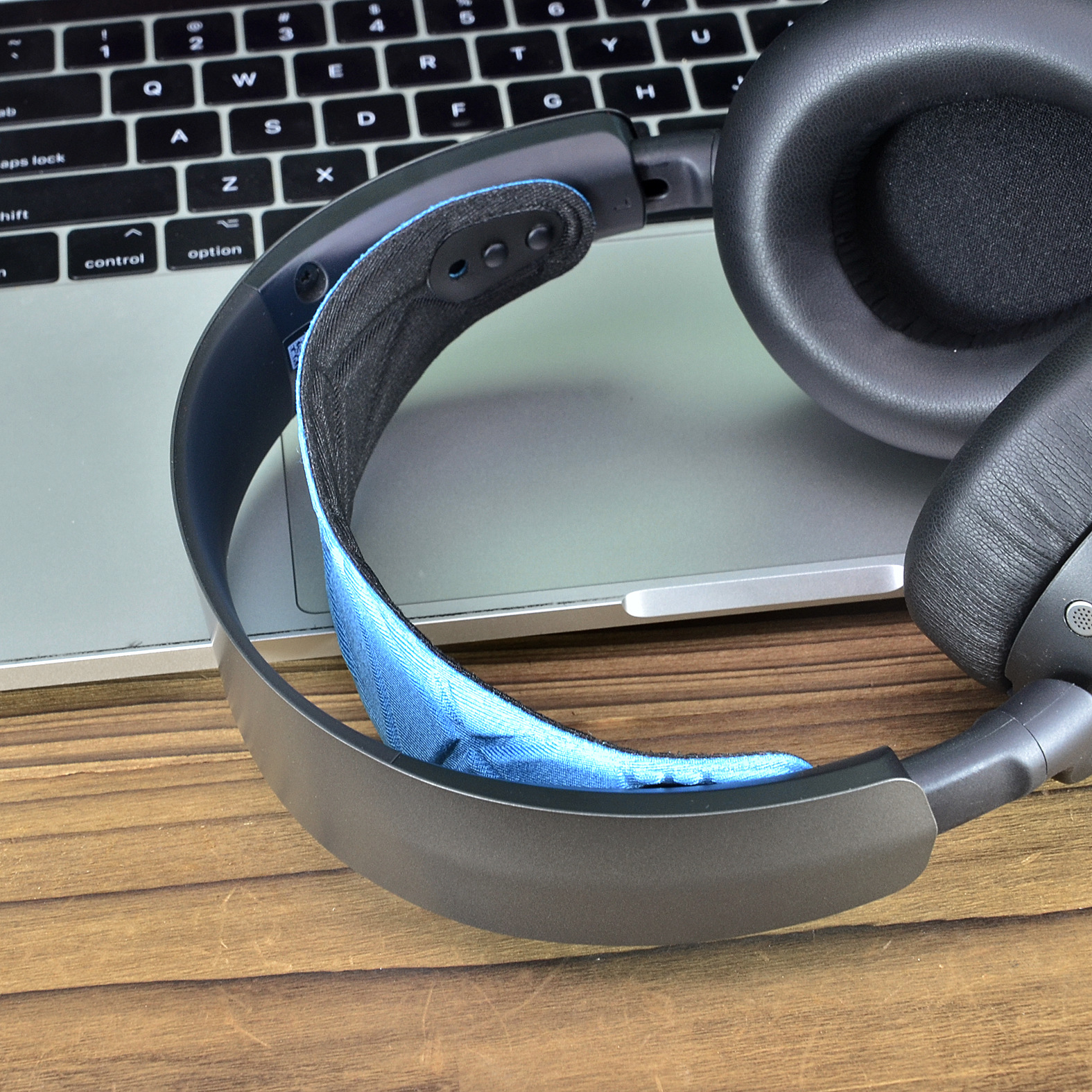 Hoofdtelefoon op een laptop. De hoofdtelefoon is grijs met een blauwe stof op de hoofdband.