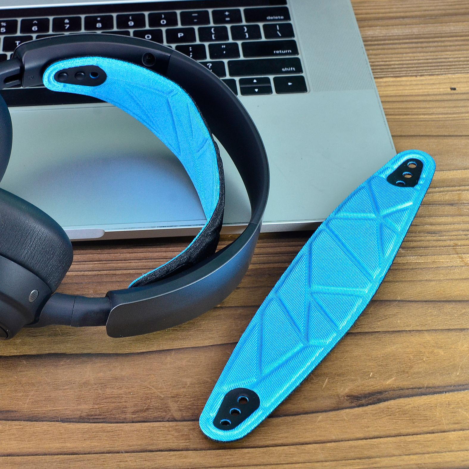 Een headset met een blauwe hoofdband en een los blauw kussen, geplaatst op een houten tafel.