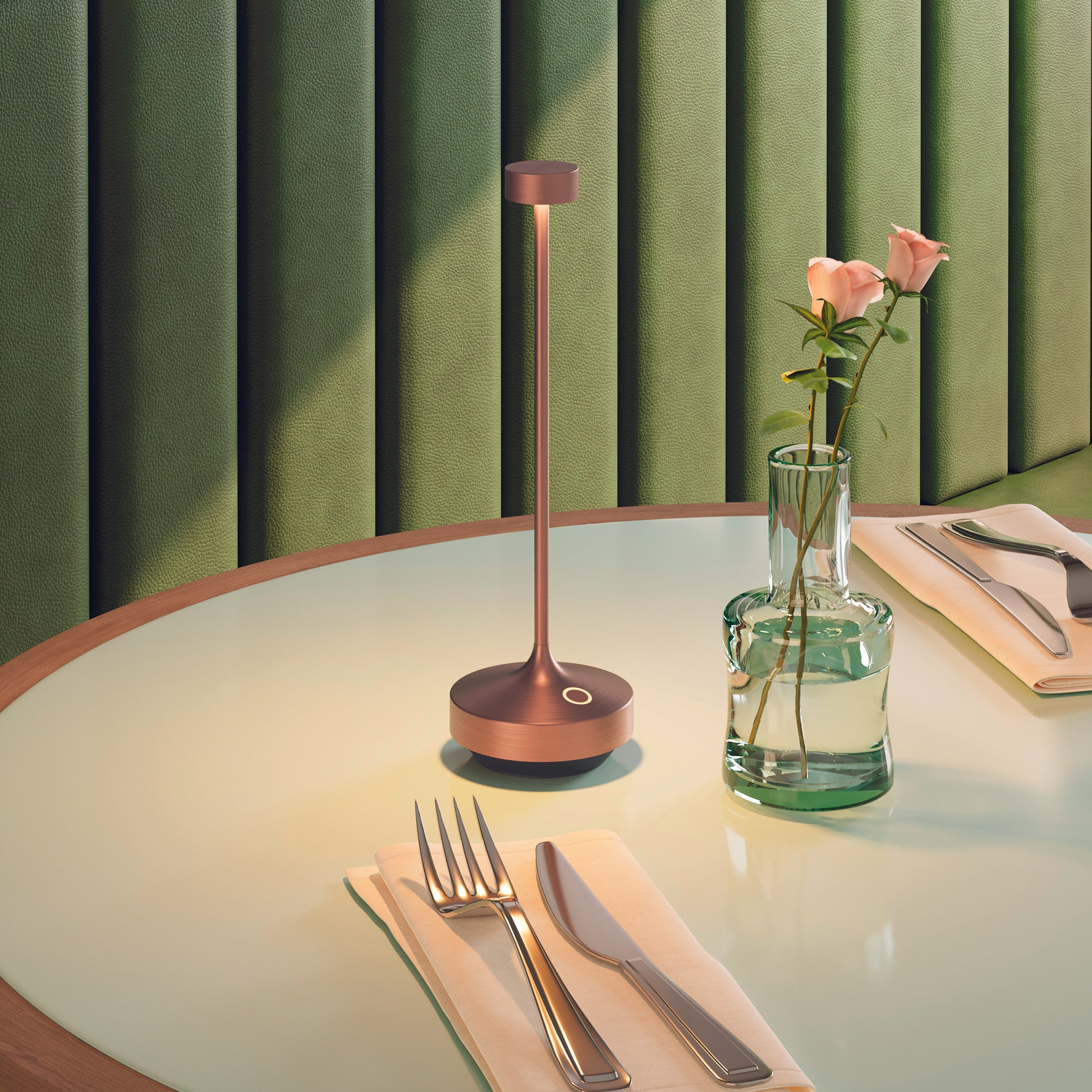 Tisch mit Lampe, Blumen in einer Vase und Besteck. Grüne Wand im Hintergrund.