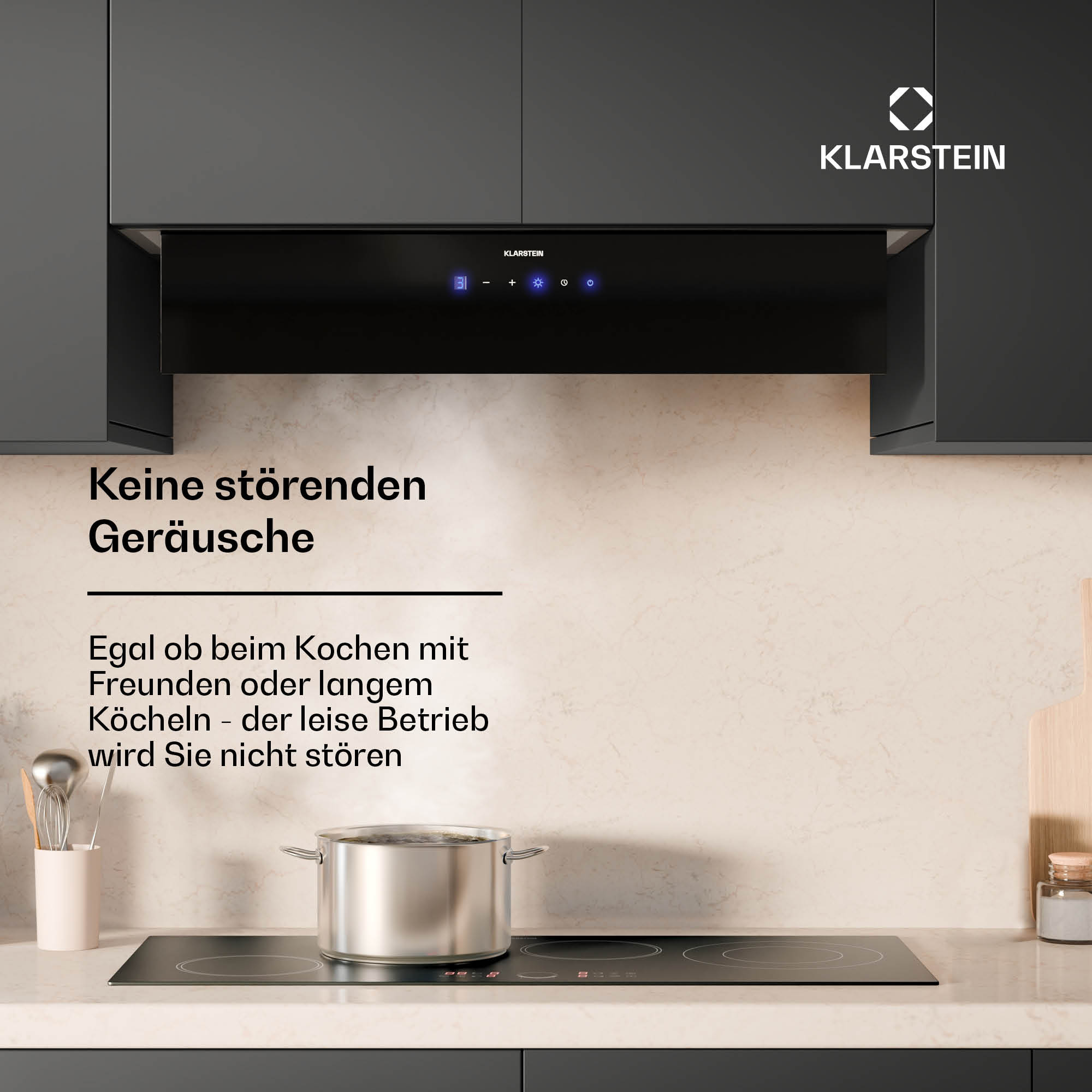 Eine schwarze Dunstabzugshaube über einem schwarzen Kochfeld mit einem Topf darauf.