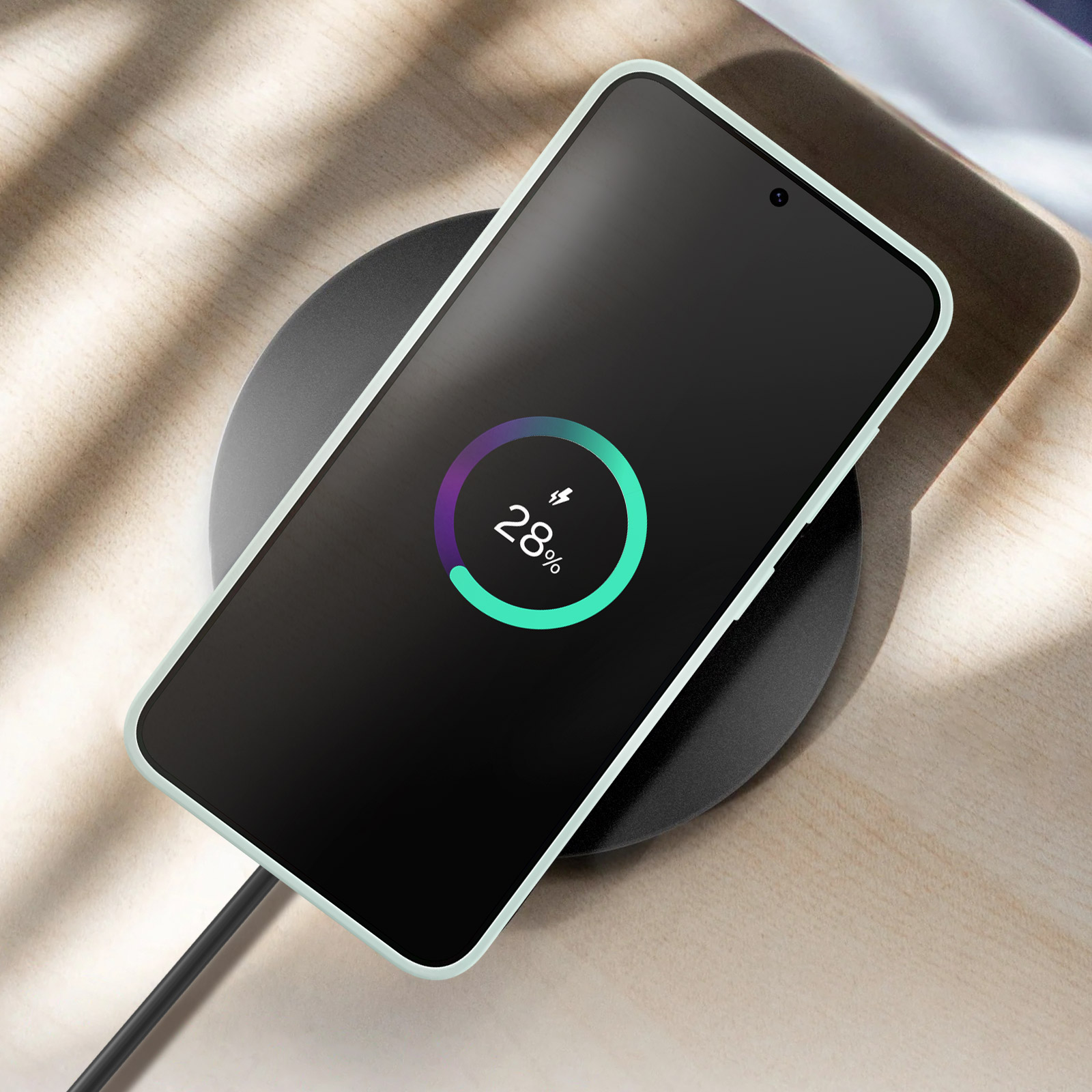 Uno smartphone in carica wireless su un pad nero, che mostra il 28% di carica.