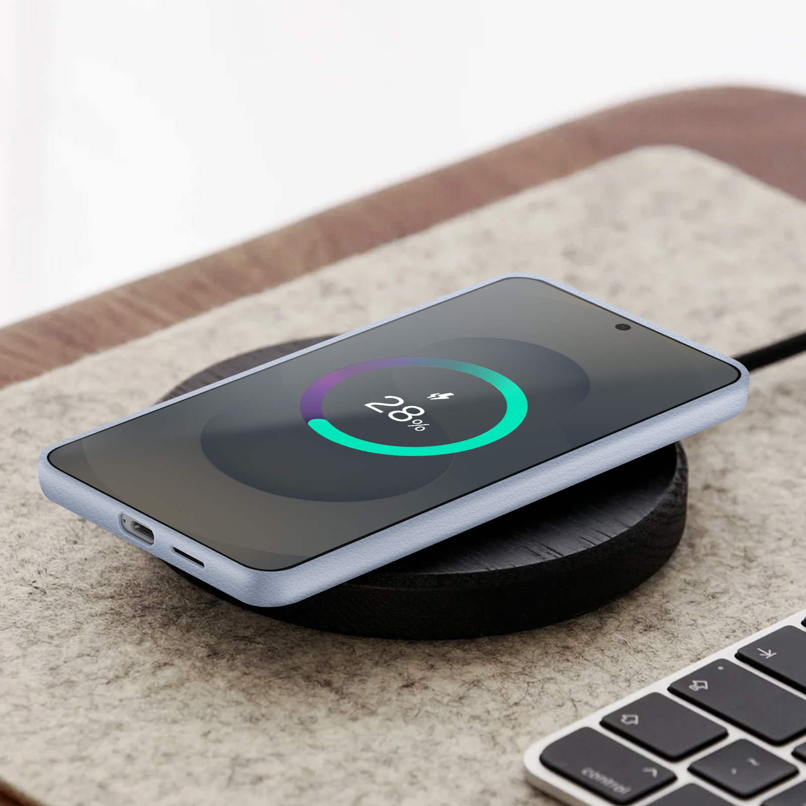 Niebieski telefon na czarnej ładowarce bezprzewodowej. Ekran pokazuje 28% naładowania.