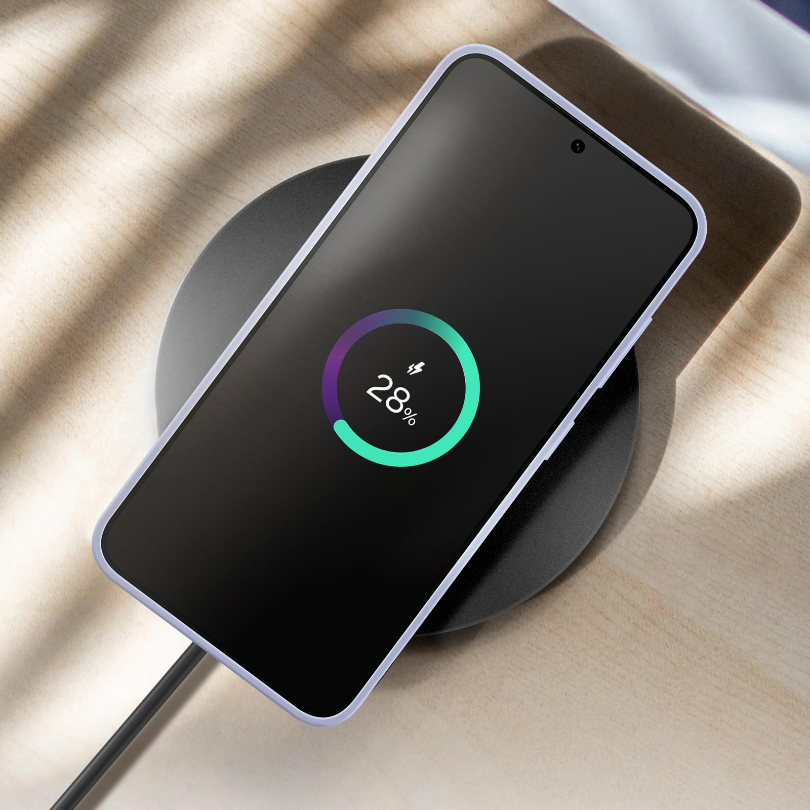 Un teléfono cargando de forma inalámbrica en una almohadilla negra, mostrando un 28% de carga.
