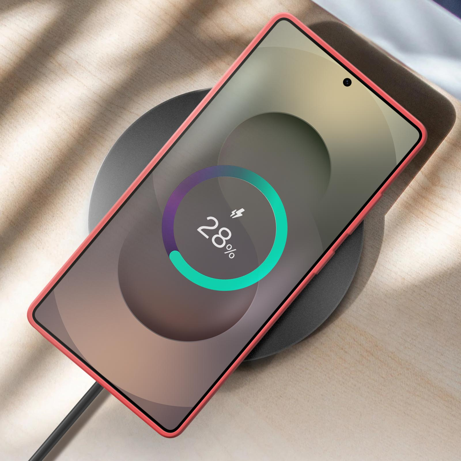 Een smartphone op een draadloze oplader. De telefoon is rood en laadt voor 28% op het scherm.