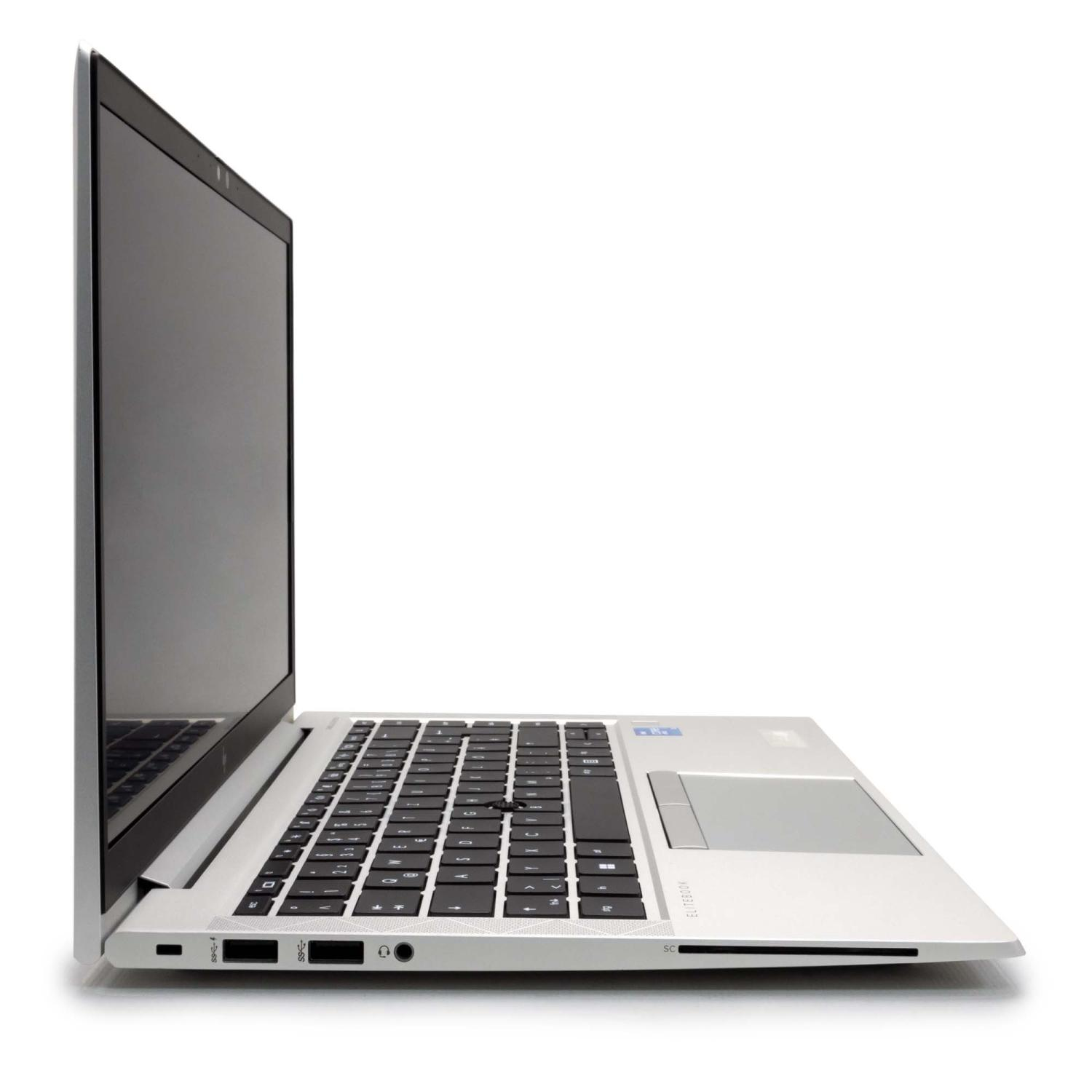 Ein silberner Laptop im Profil, geöffnet, auf einer weißen Oberfläche mit schwarzer Tastatur.