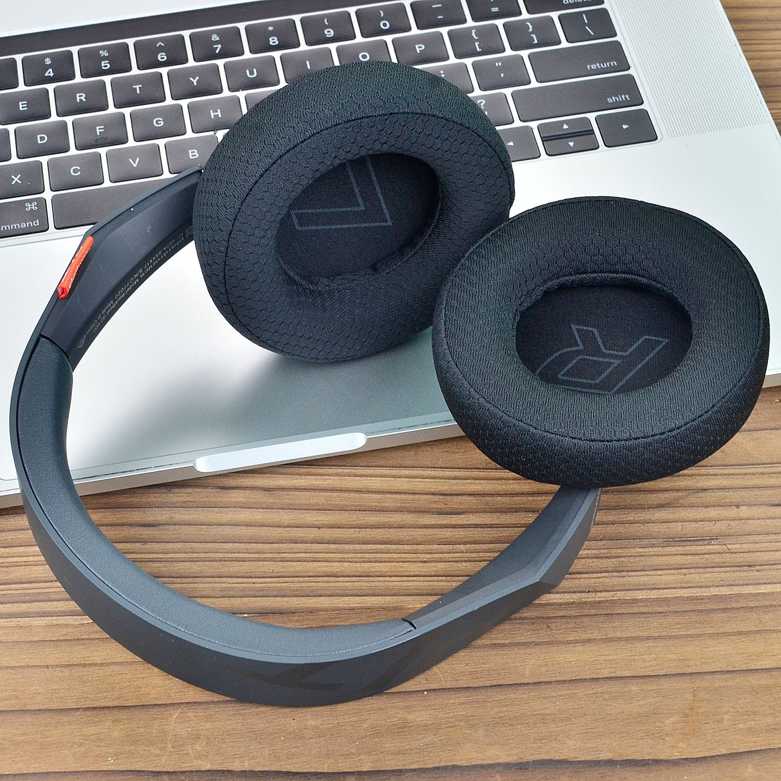 Słuchawki na klawiaturze laptopa. Słuchawki są czarne z czerwonymi akcentami i logo.