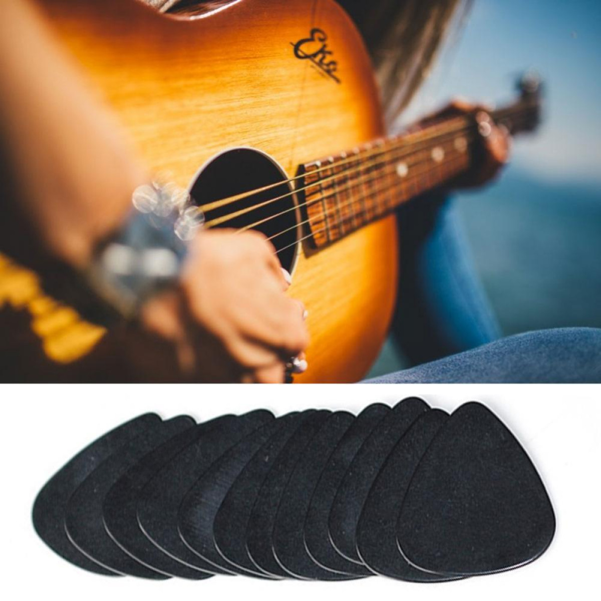 Eine Person spielt Gitarre, die Gitarrenplektren liegen auf dem Tisch. Die Gitarre ist braun, die Plektren sind schwarz.