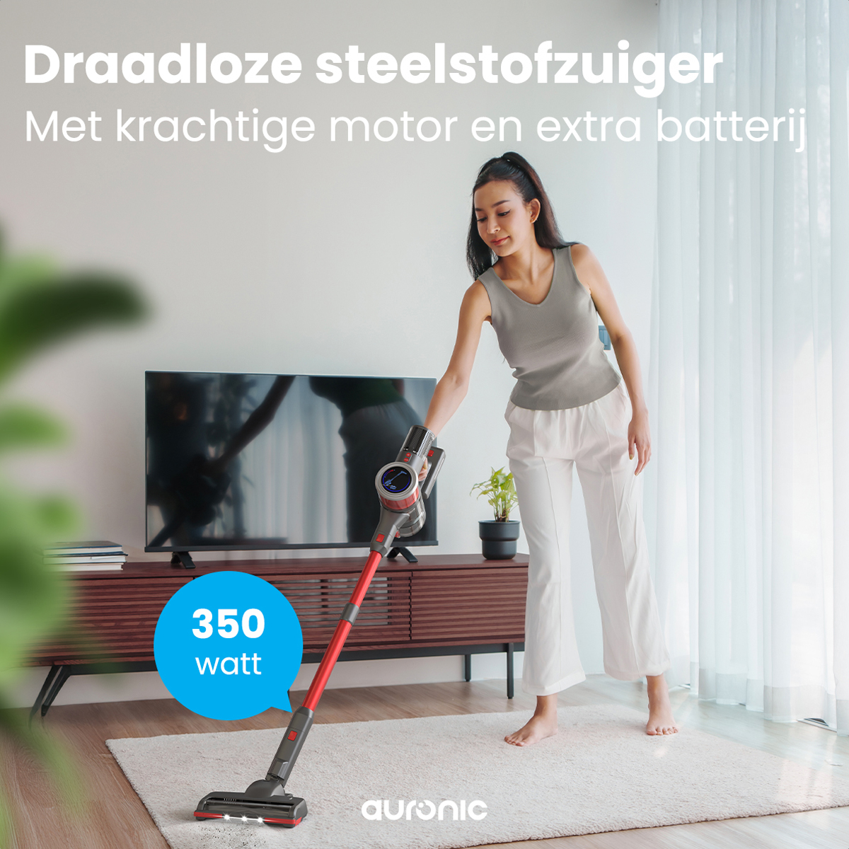 Eine Frau benutzt einen roten und schwarzen kabellosen Staubsauger. 350 Watt-Label sichtbar.