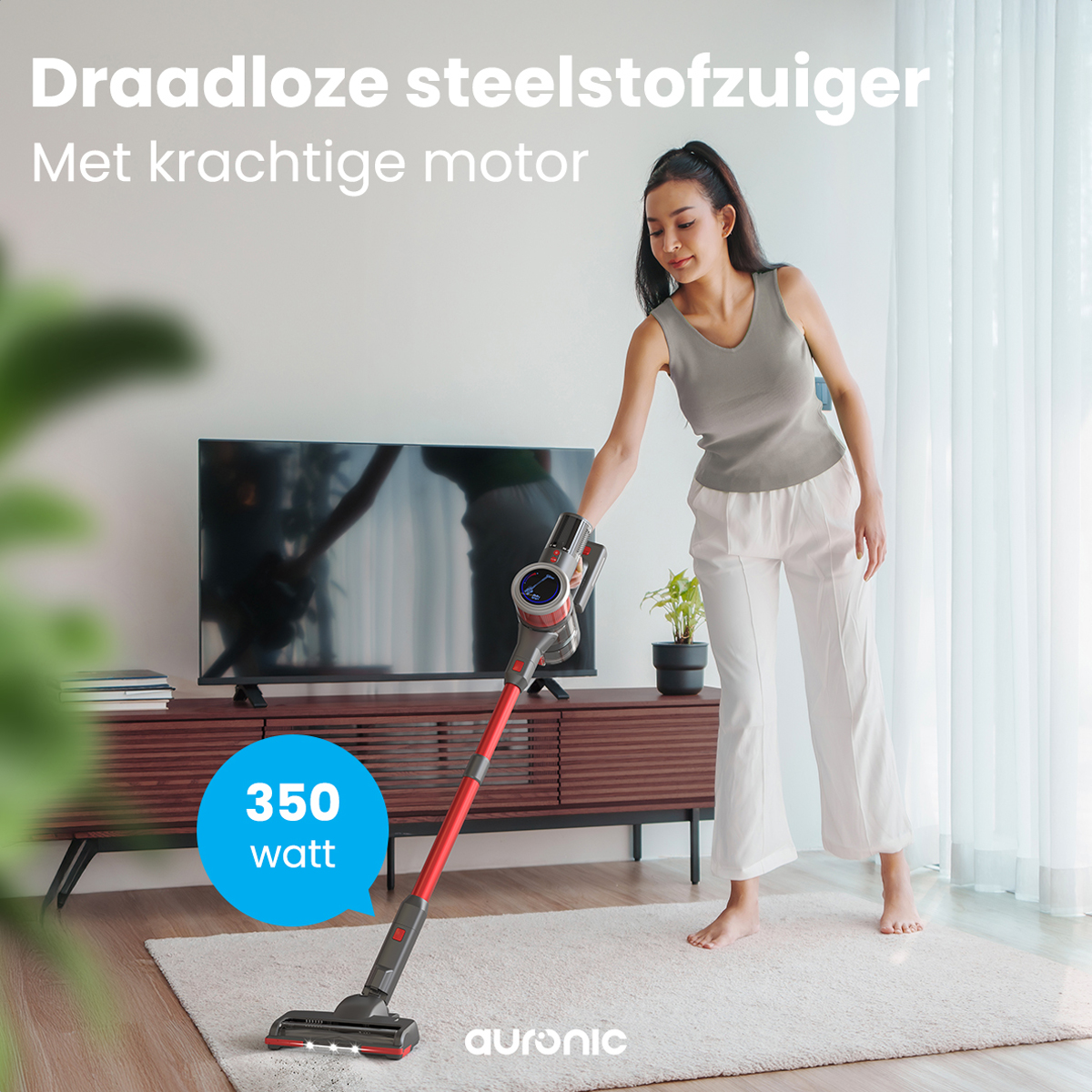Femme passe l'aspirateur sur un tapis. Un aspirateur sans fil rouge et noir.