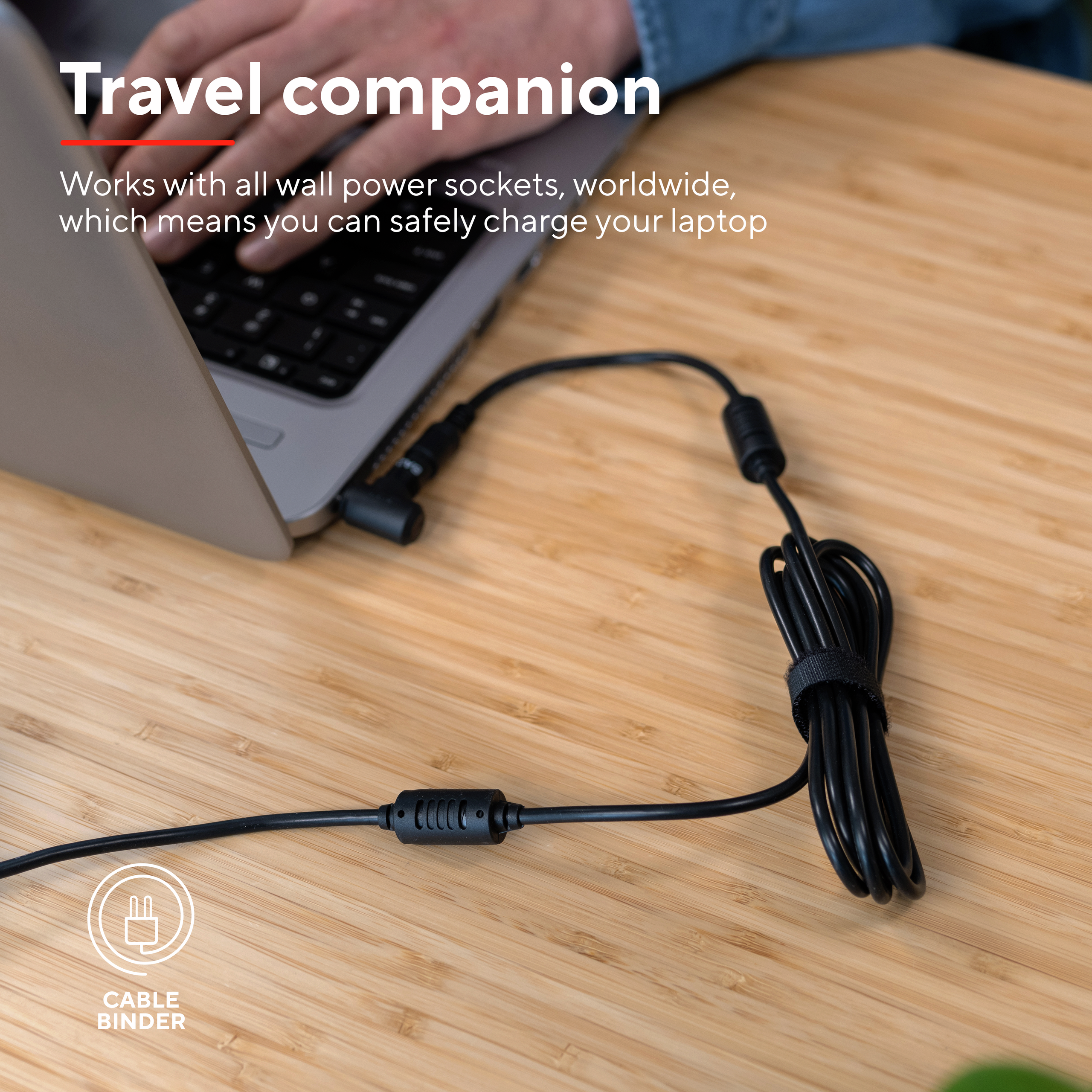 Laptop-Ladekabel an einem Laptop auf einem Holztisch angeschlossen. Text erwähnt Reisebegleiter.