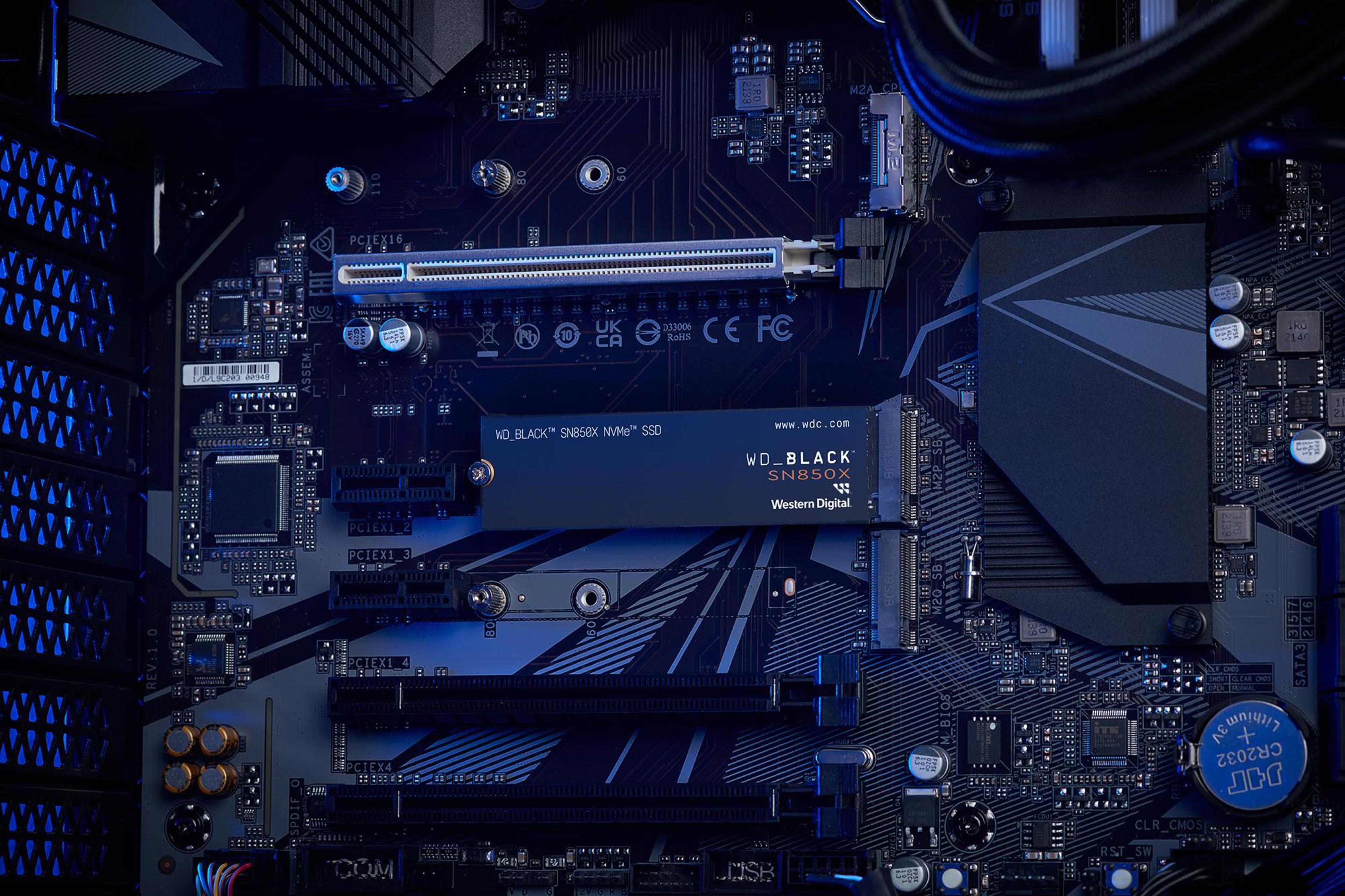 Un primer plano de una placa base de computadora con una SSD instalada, iluminada con luz azul.