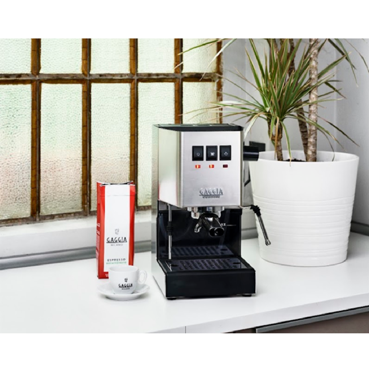 Ekspres do kawy Gaggia z akcesoriami na białym blacie. Obecna jest roślina i espresso.