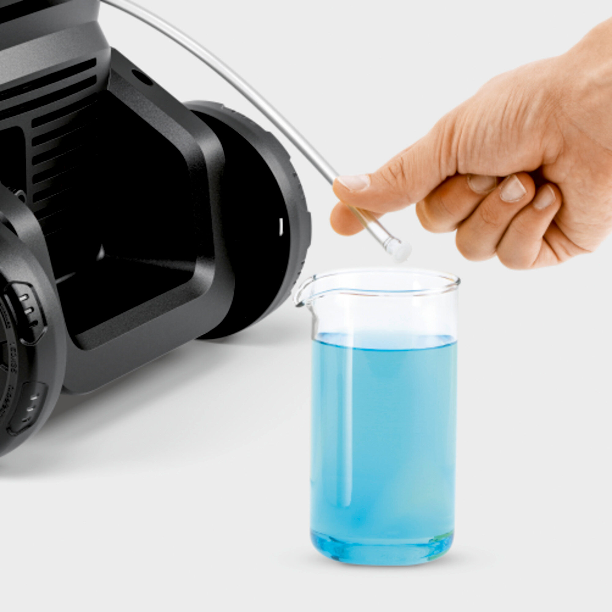 Mano versa liquido blu da un becher in una macchina.