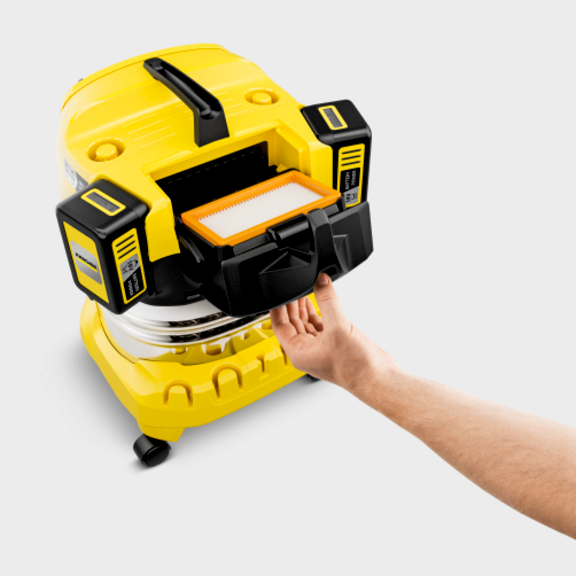 Aspirapolvere giallo con filtro controllato da una mano.