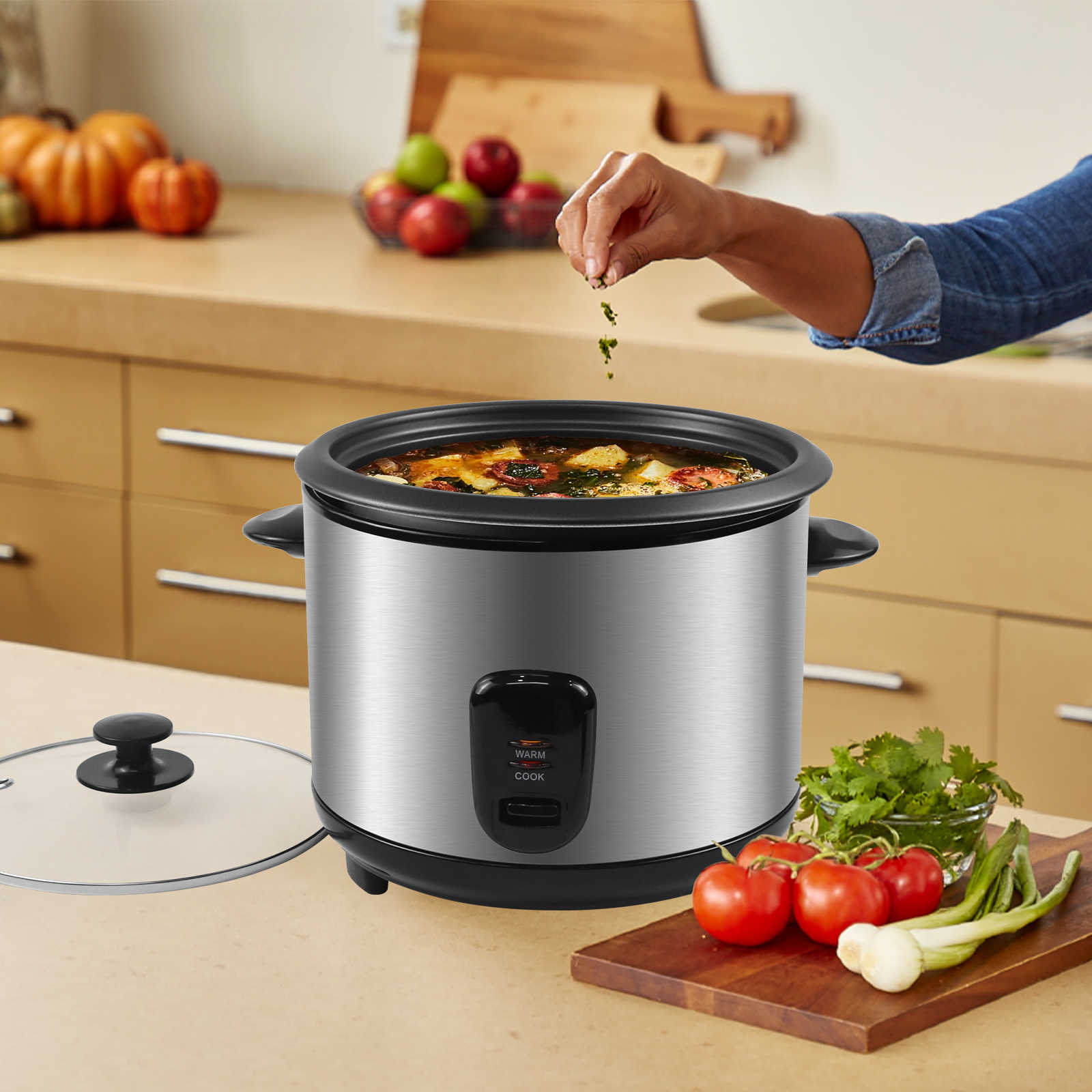 Silberner Slow Cooker, Gemüse und Kräuter werden hinzugefügt, neben einem Holzschneidebrett.