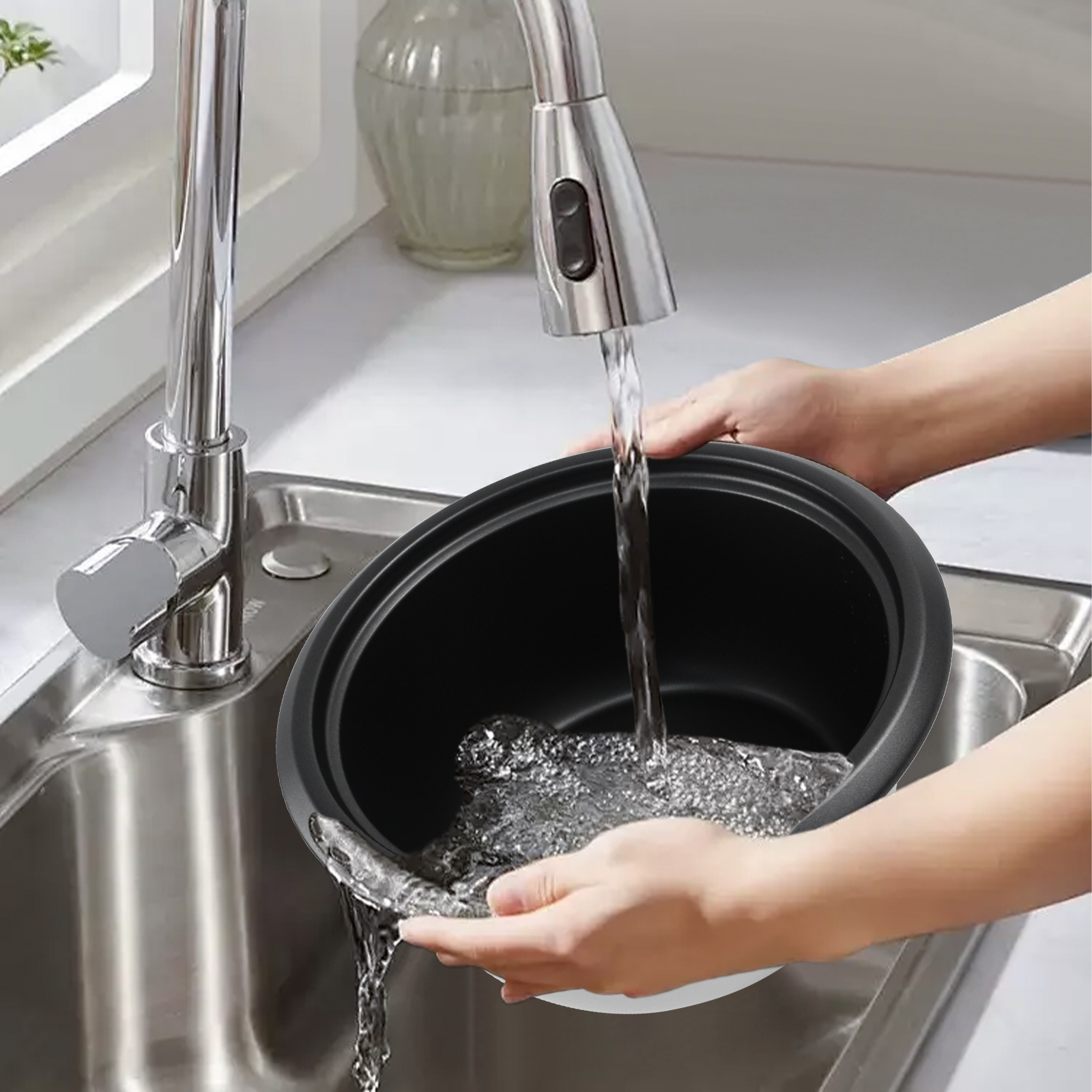 Hände, die einen schwarzen Topf unter einem Wasserhahn in einem Edelstahlbecken waschen.