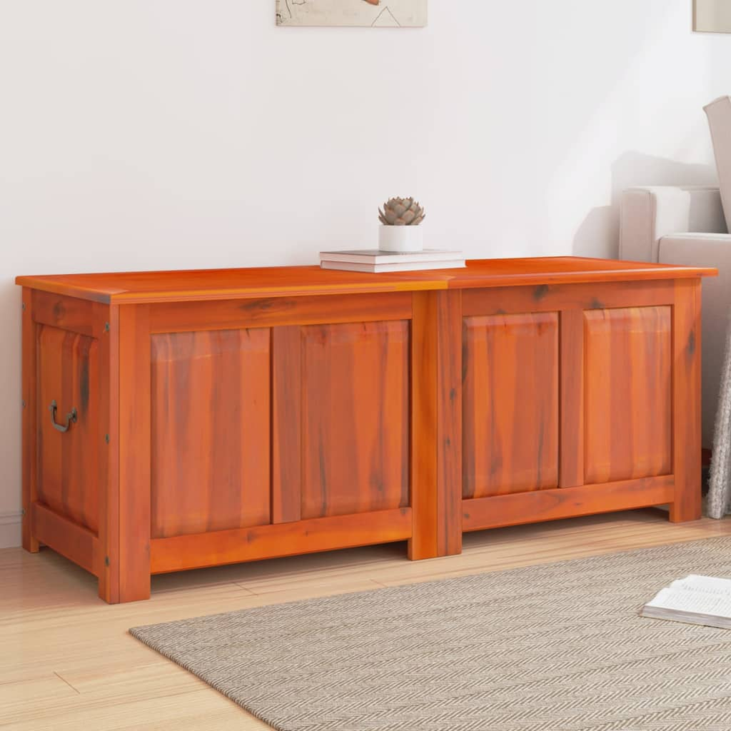 Holztruhe mit orangefarbenem Finish. Sie hat zwei Türen, Griffe und steht auf einem Teppich in der Nähe eines Sofas.