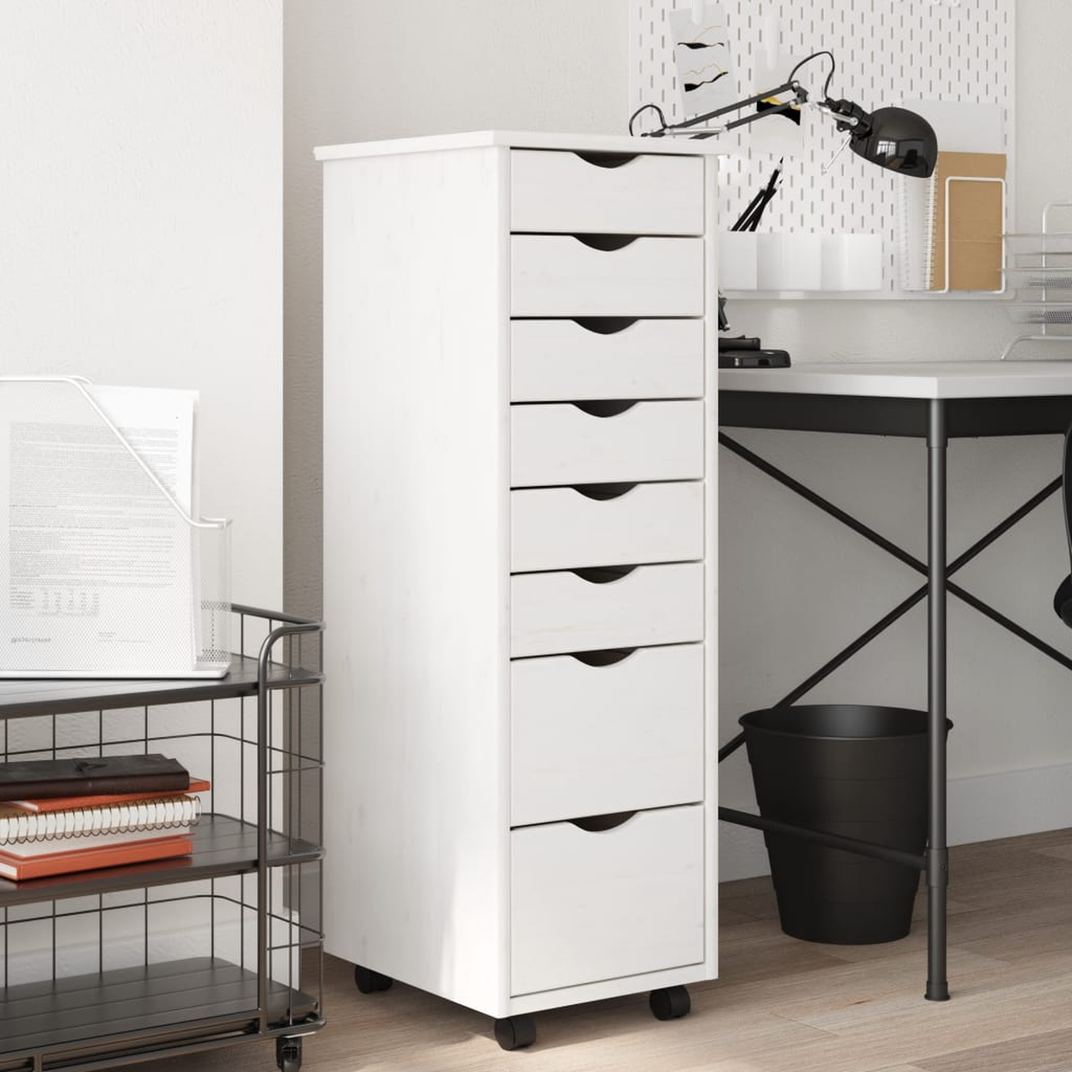 Hoher weißer Schrank mit mehreren Schubladen, auf Rädern vor weißer Wand.