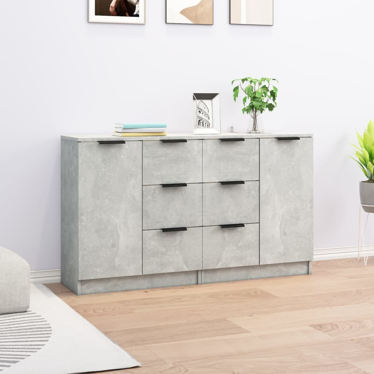Ein Sideboard im grauen Beton-Stil mit Schubladen und Türen vor einer weißen Wand und Holzboden.