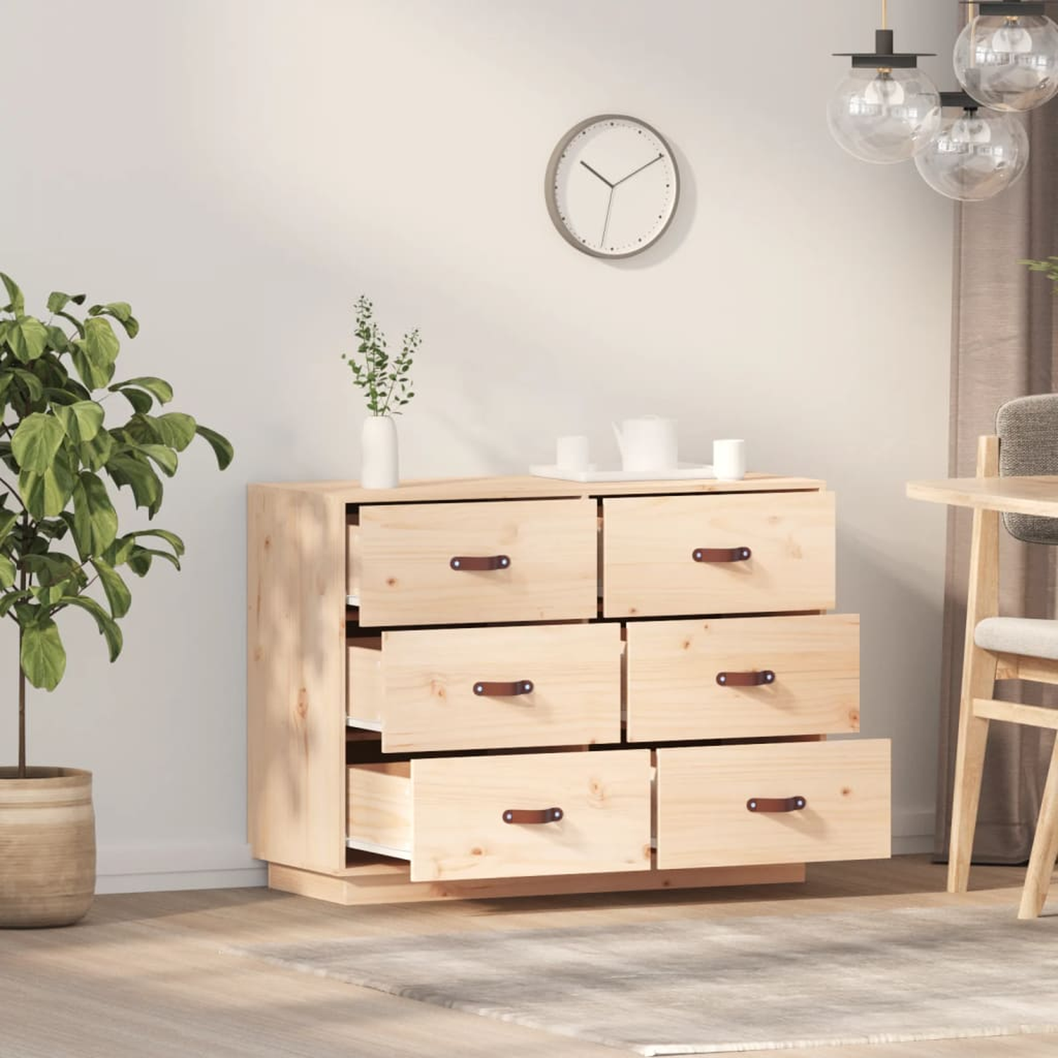 Eine helle Holzkommode mit offenen Schubladen und Dekoration auf dem Tisch.