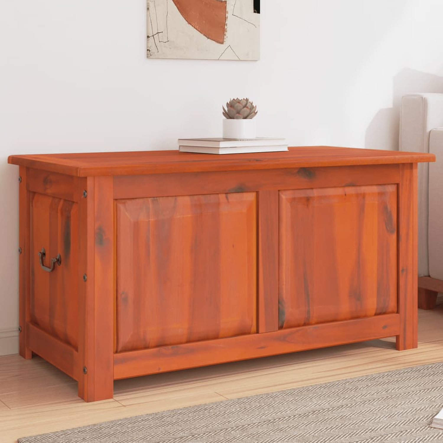 Eine Holzkiste mit Griff auf einem Teppich. Die Truhe ist orange.
