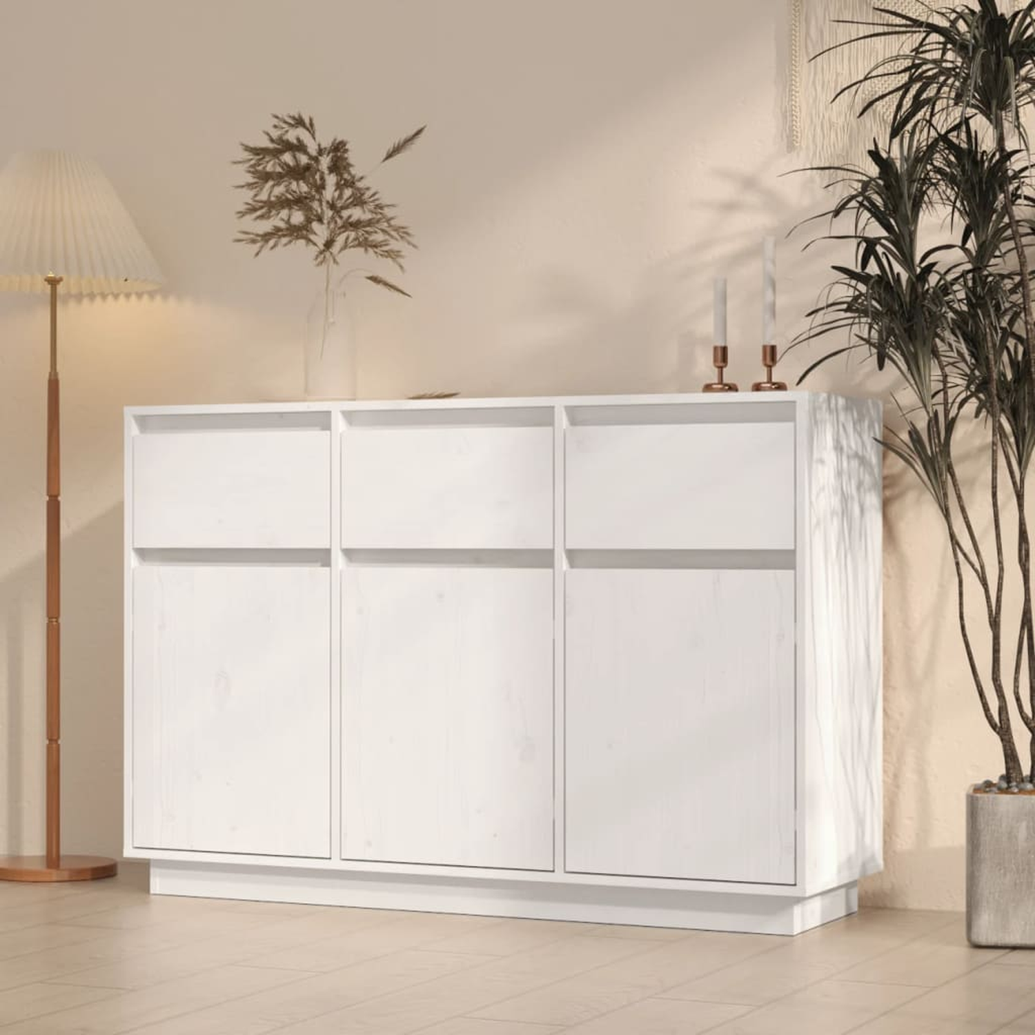 Weißer Schrank mit drei Türen, mit Kerzen und Pflanze in der Nähe.