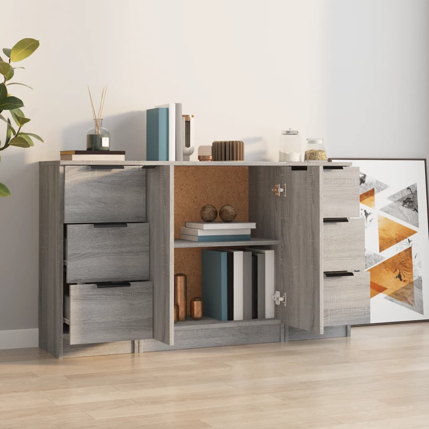 Ein graues Sideboard mit offenen Türen. Bücher, Deko und ein Bild darauf.