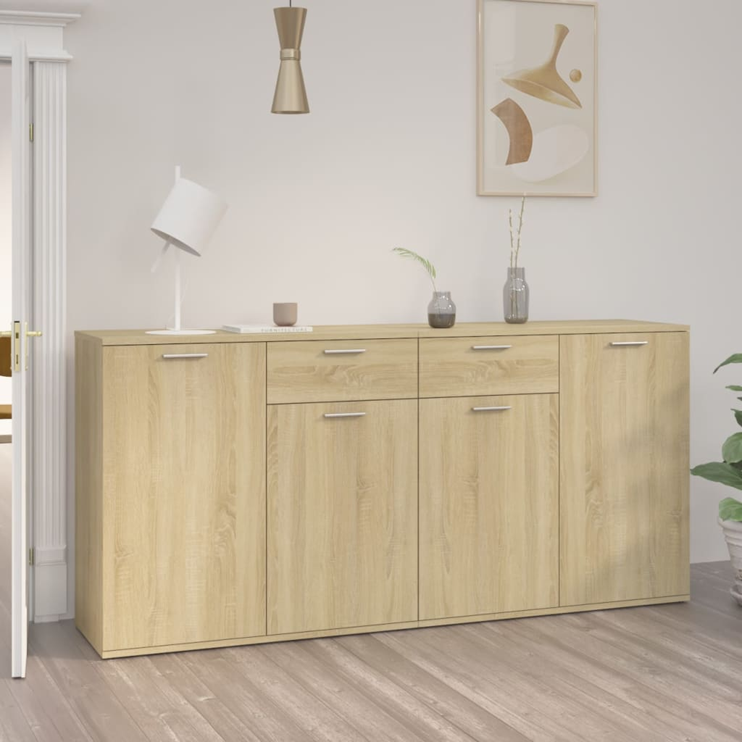 Eine helle Holz-Anrichte mit Schubladen und Türen, eine Tischlampe und ein Gemälde an der Wand.
