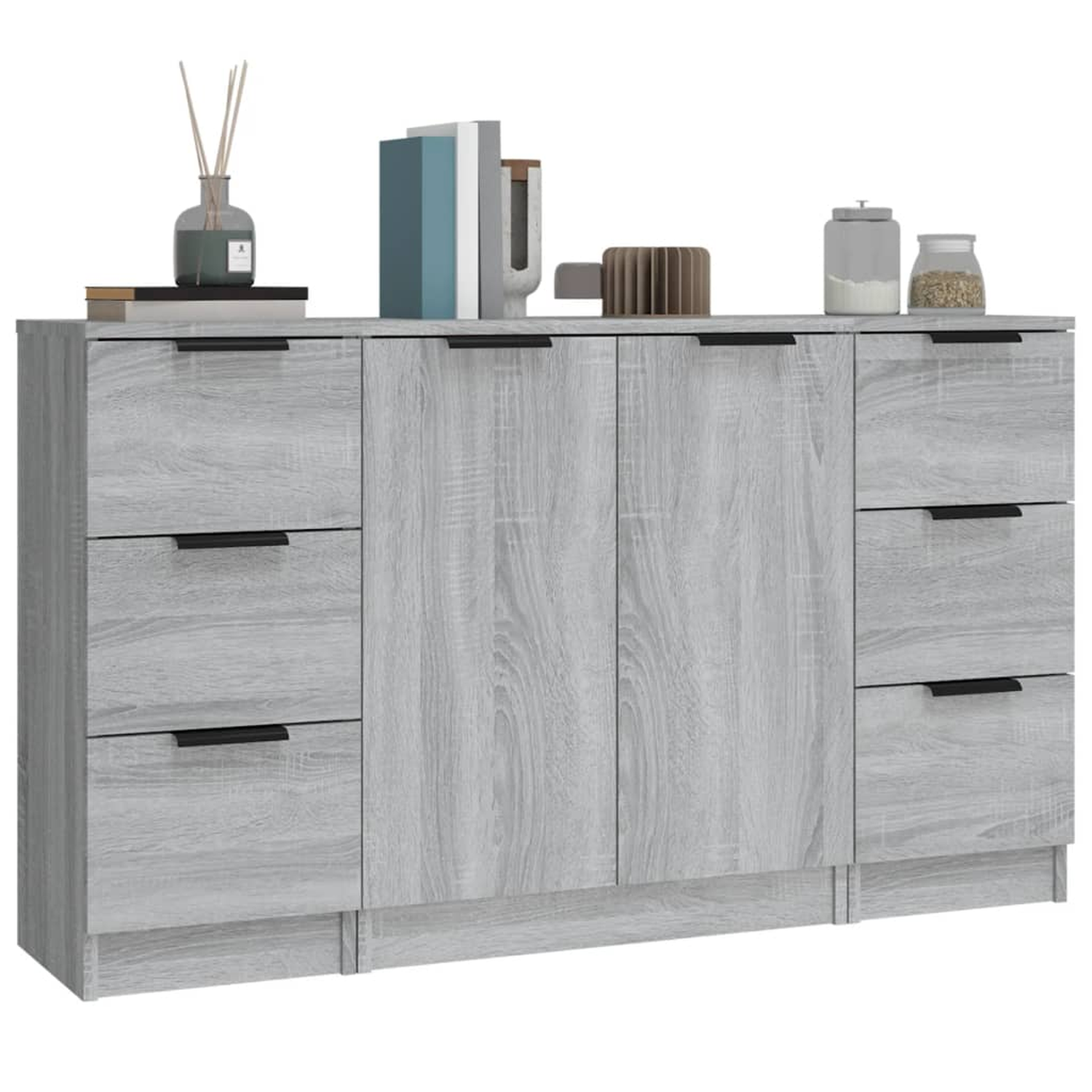 Grauer Holzschrank mit schwarzen Griffen, Schubladen und Türen, sowie Deko oben.