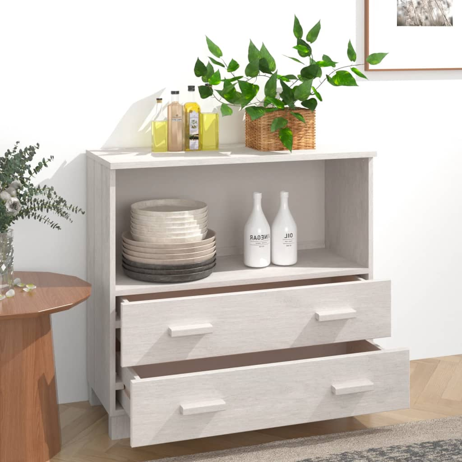 Ein weißer Holzschrank mit Schubladen und offener Oberseite, mit Geschirr und Dekor.