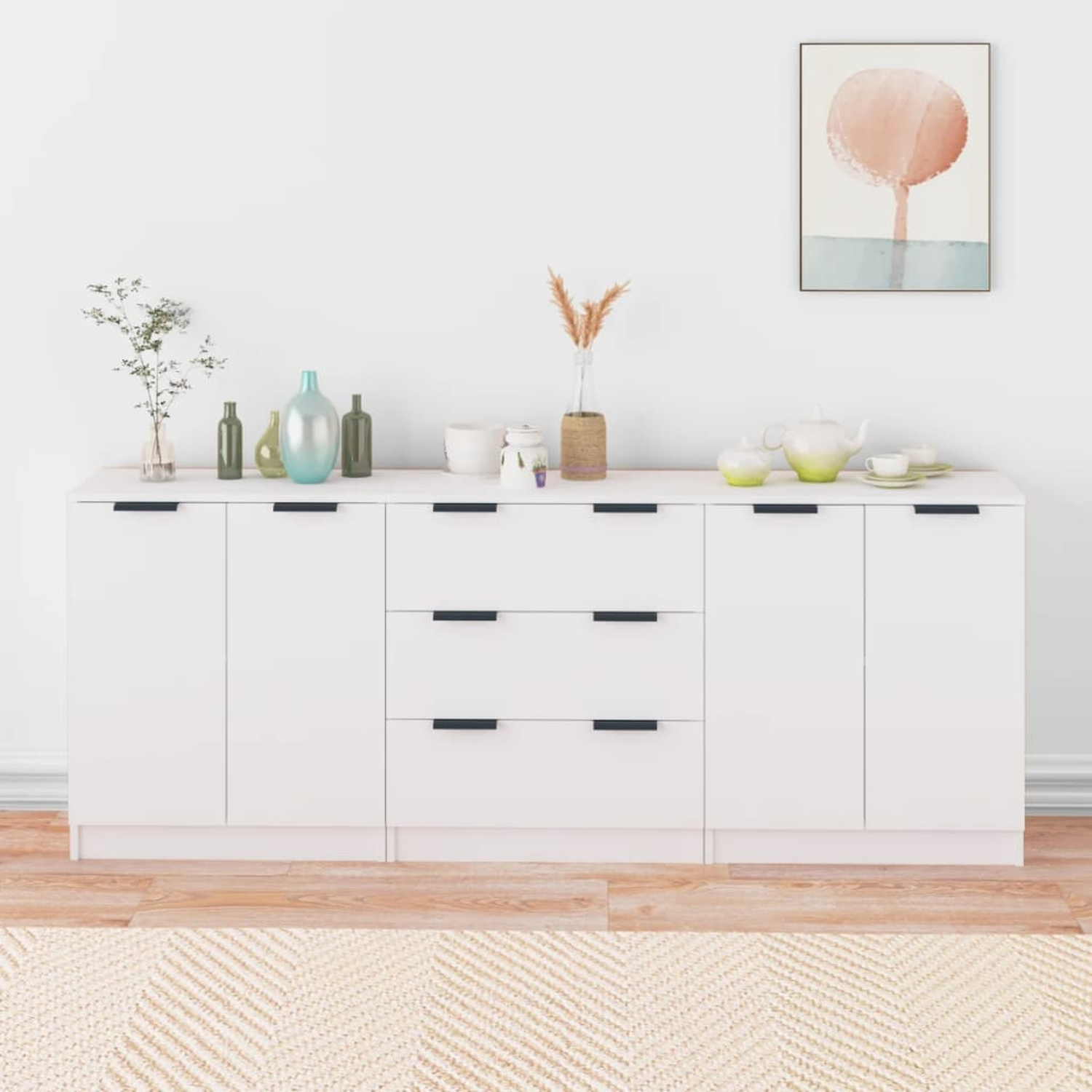 Weißes Sideboard mit schwarzen Griffen, verschiedene Deko oben, ein Gemälde.