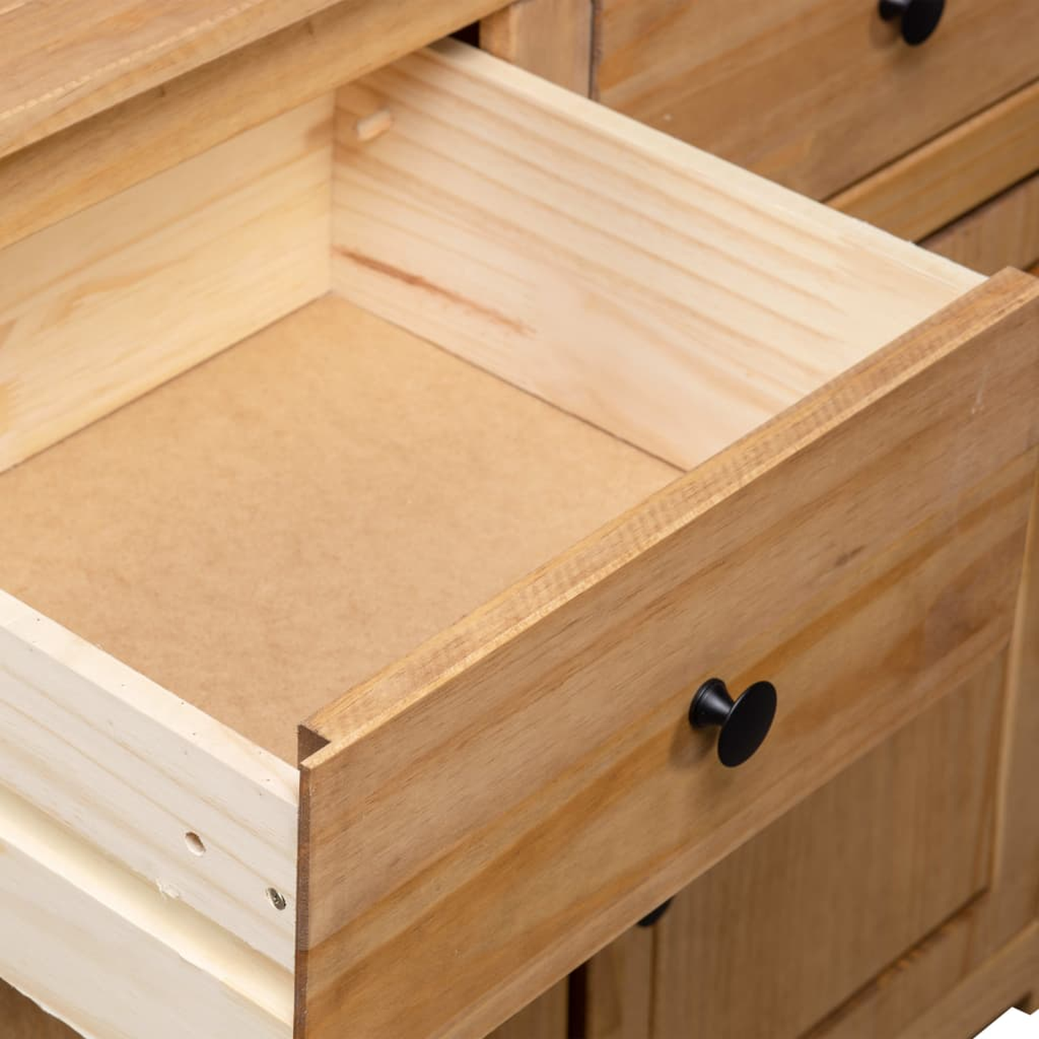 Eine offene Holzschublade mit hellbraunem Innenraum und einem schwarzen Knopf.
