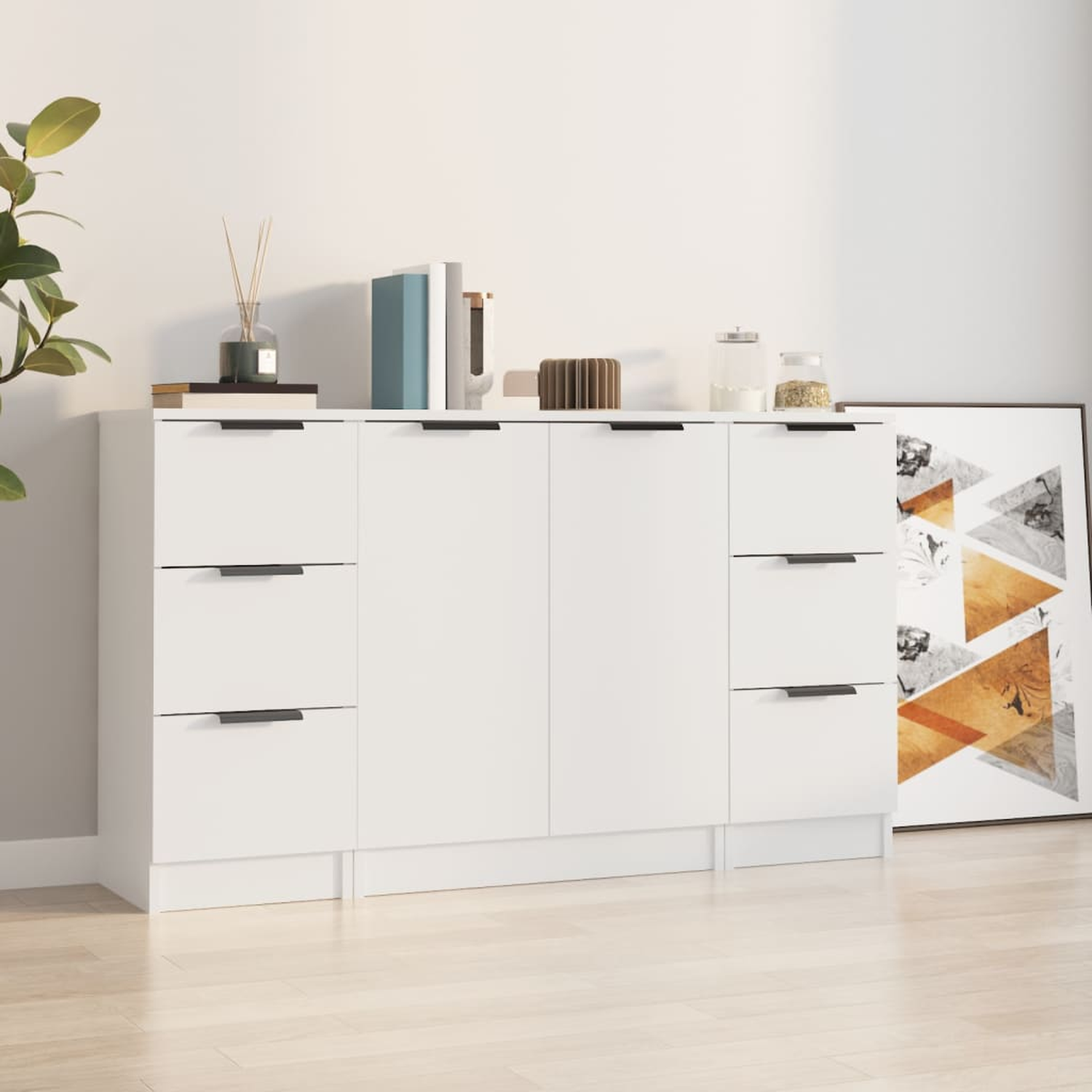 Weißer Schrank mit Schubladen und Türen. Bücher, ein Glas und ein Bilderrahmen oben.