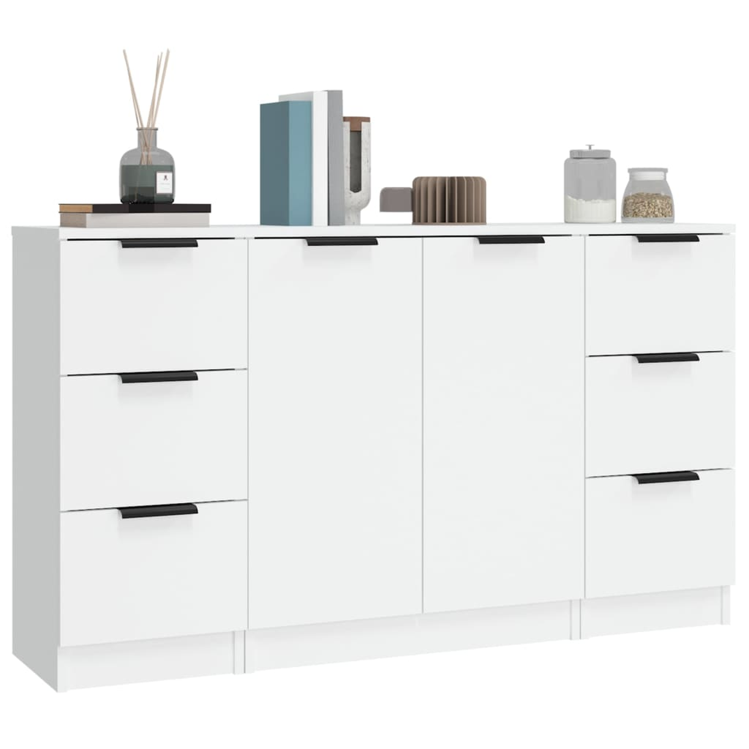 Weißer Schrank mit schwarzen Griffen, obenauf Dekoration, Bücher und Gläser. Der Schrank hat Schubladen und Türen.