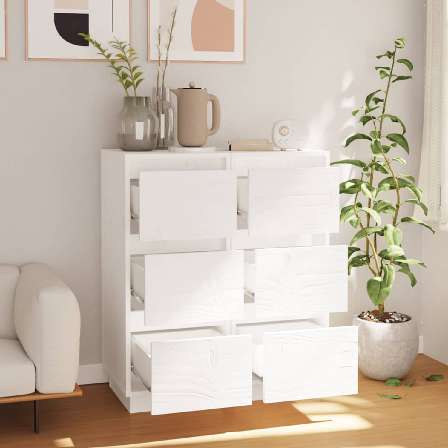 Weiße Kommode mit offenen Schubladen, Pflanze, Vase und Dekoration.